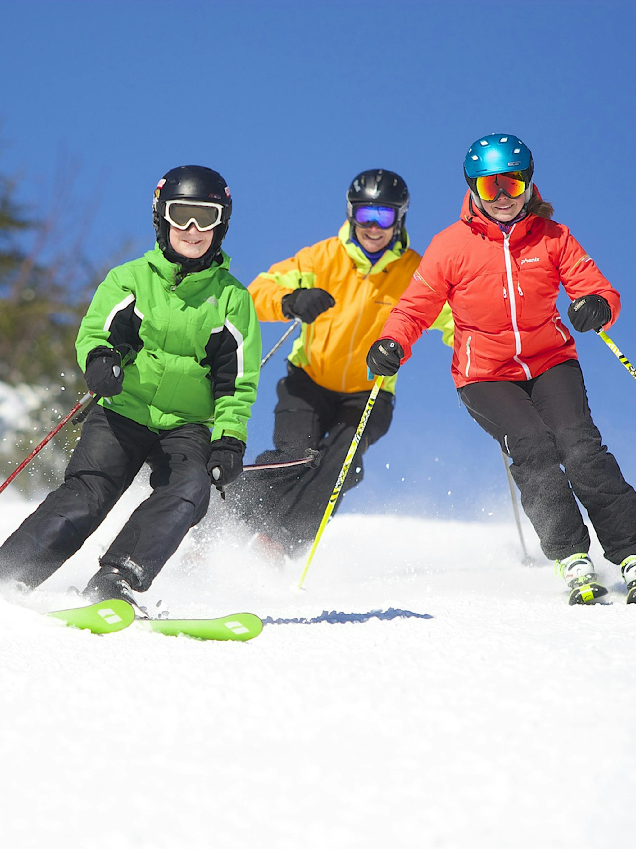 Three friends ski down a snowy slope at Okemo