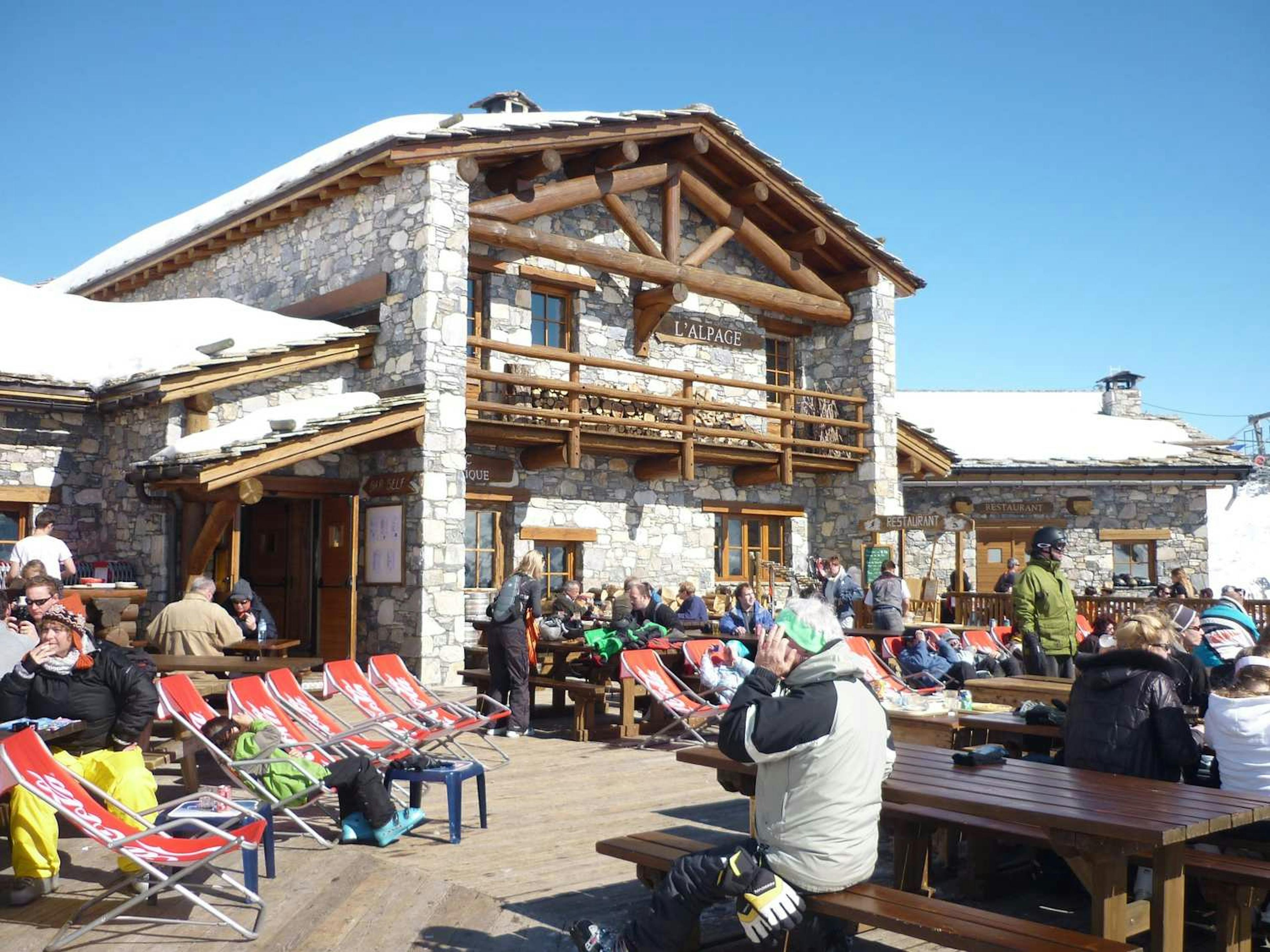 People relaxing outside a building in Tignes, sharing laughs and good times in a cozy outdoor setting.