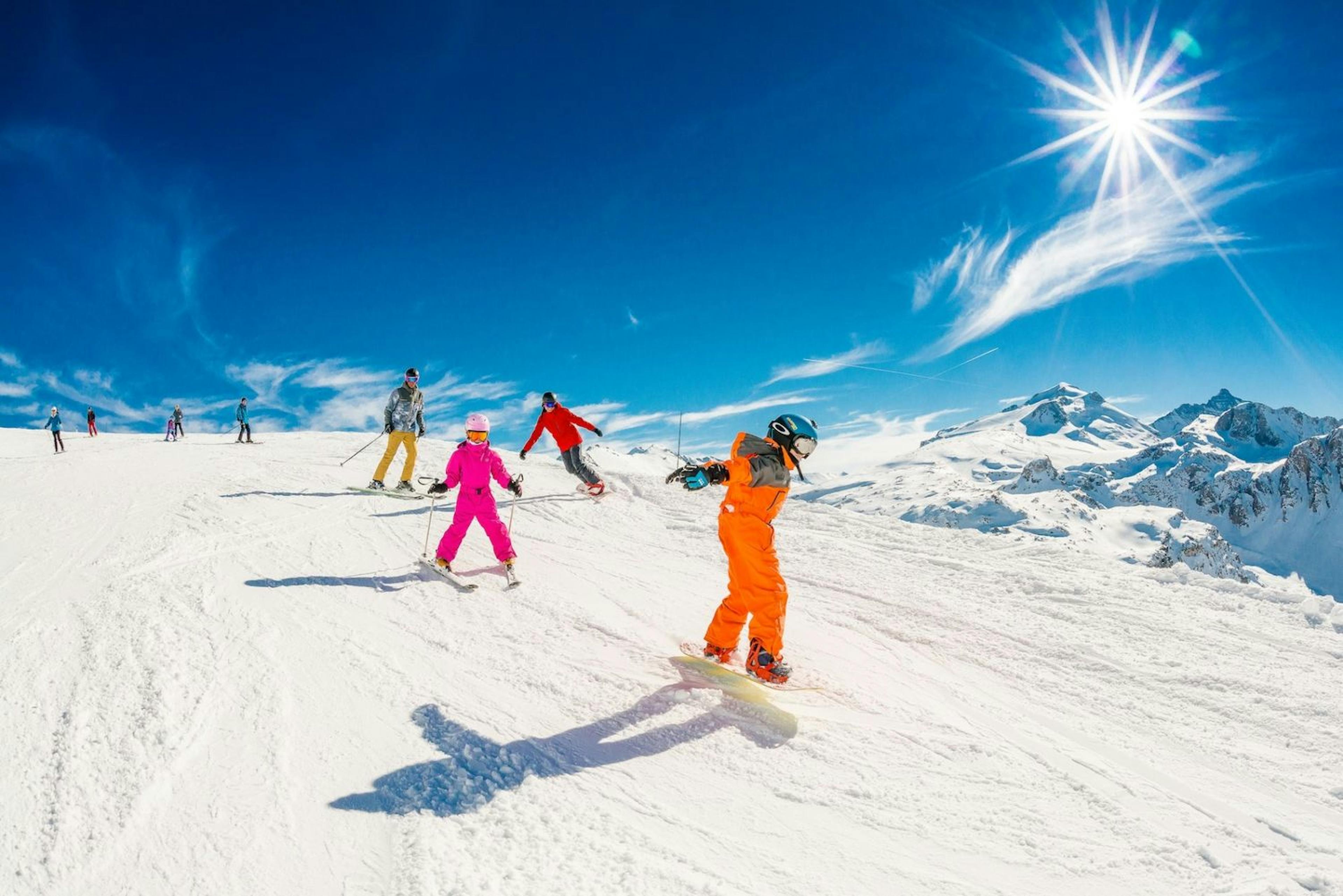 Friends having a blast in Tignes on a sunny day, with vibrant snow and a stunning mountain backdrop.