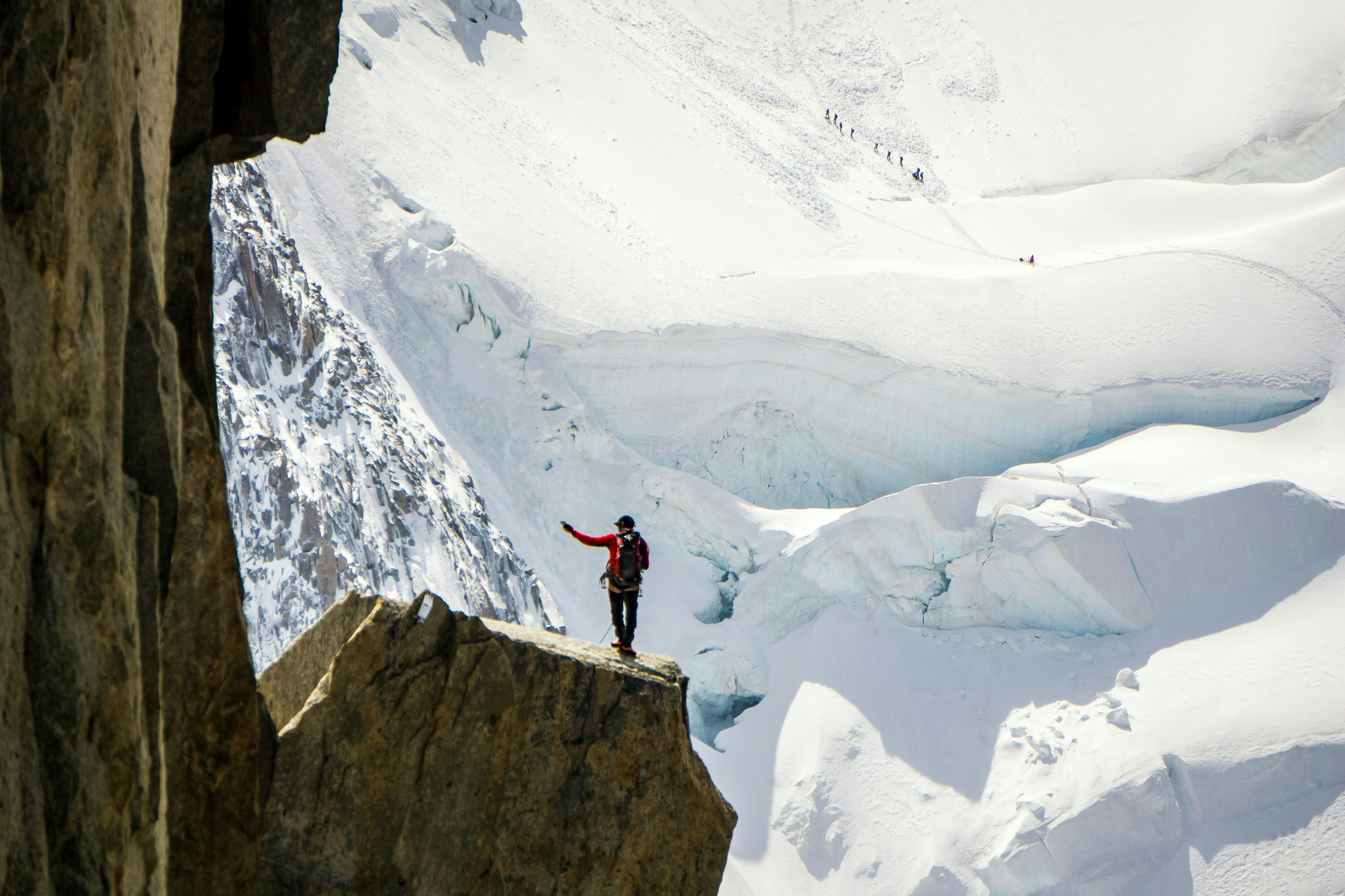 a skier stands on the peak of aiguille du midi in France with glaciers draped in the background

