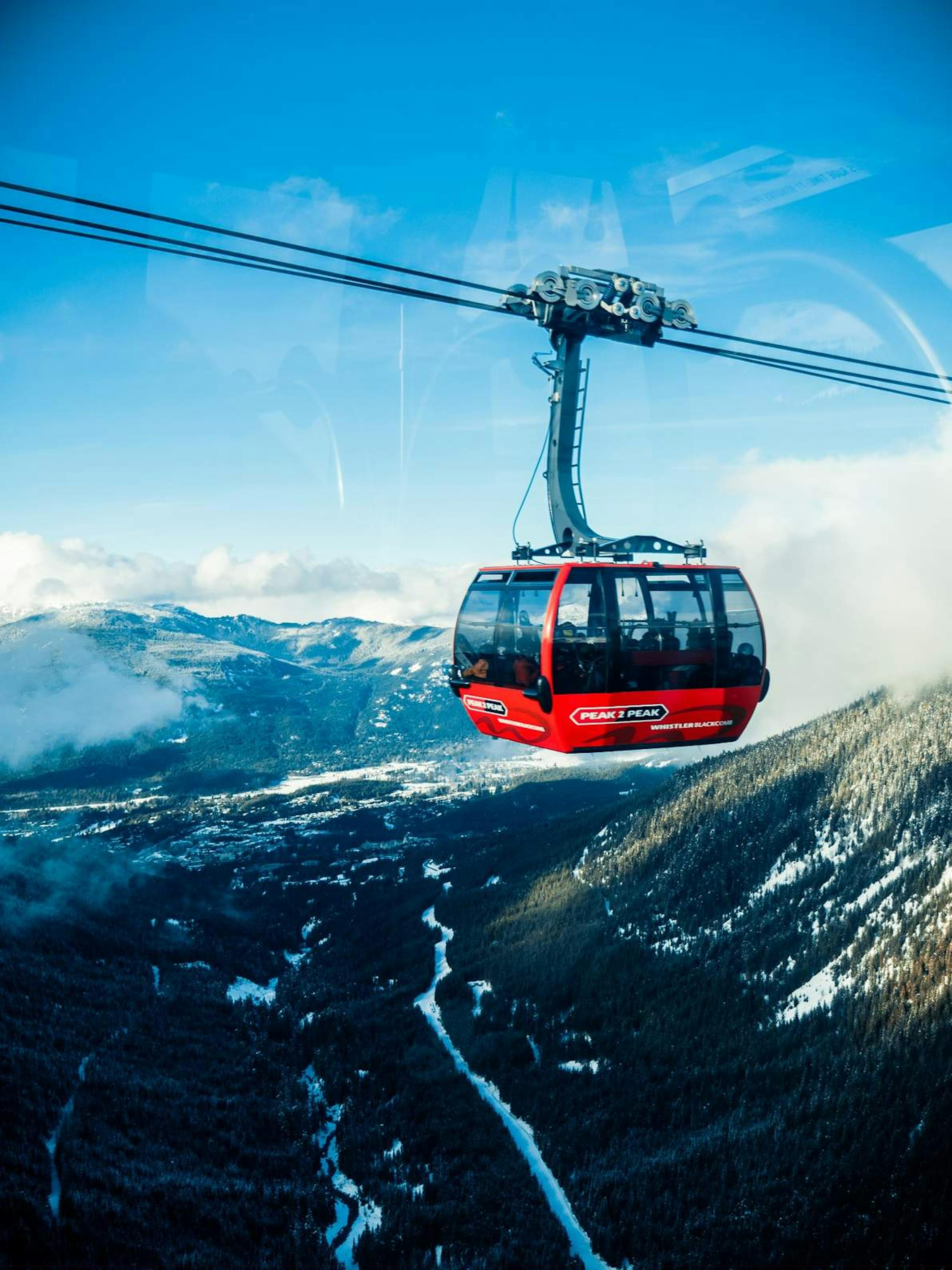 A cable car glides above the stunning mountain range of Whistler Blackcomb ski resort