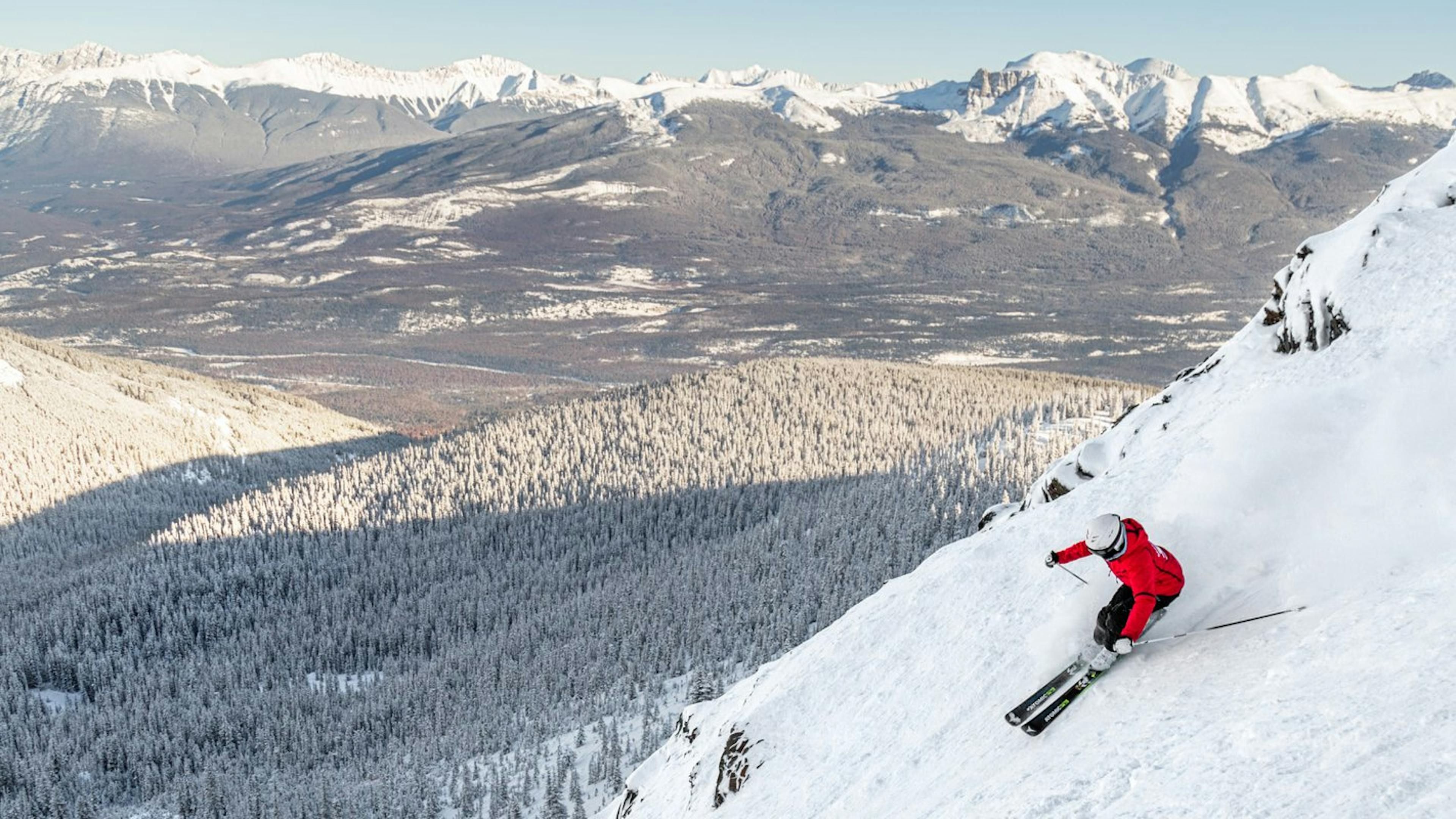 Woman in red jacket skiing the Tres Hombres ski run in Marmot Basin