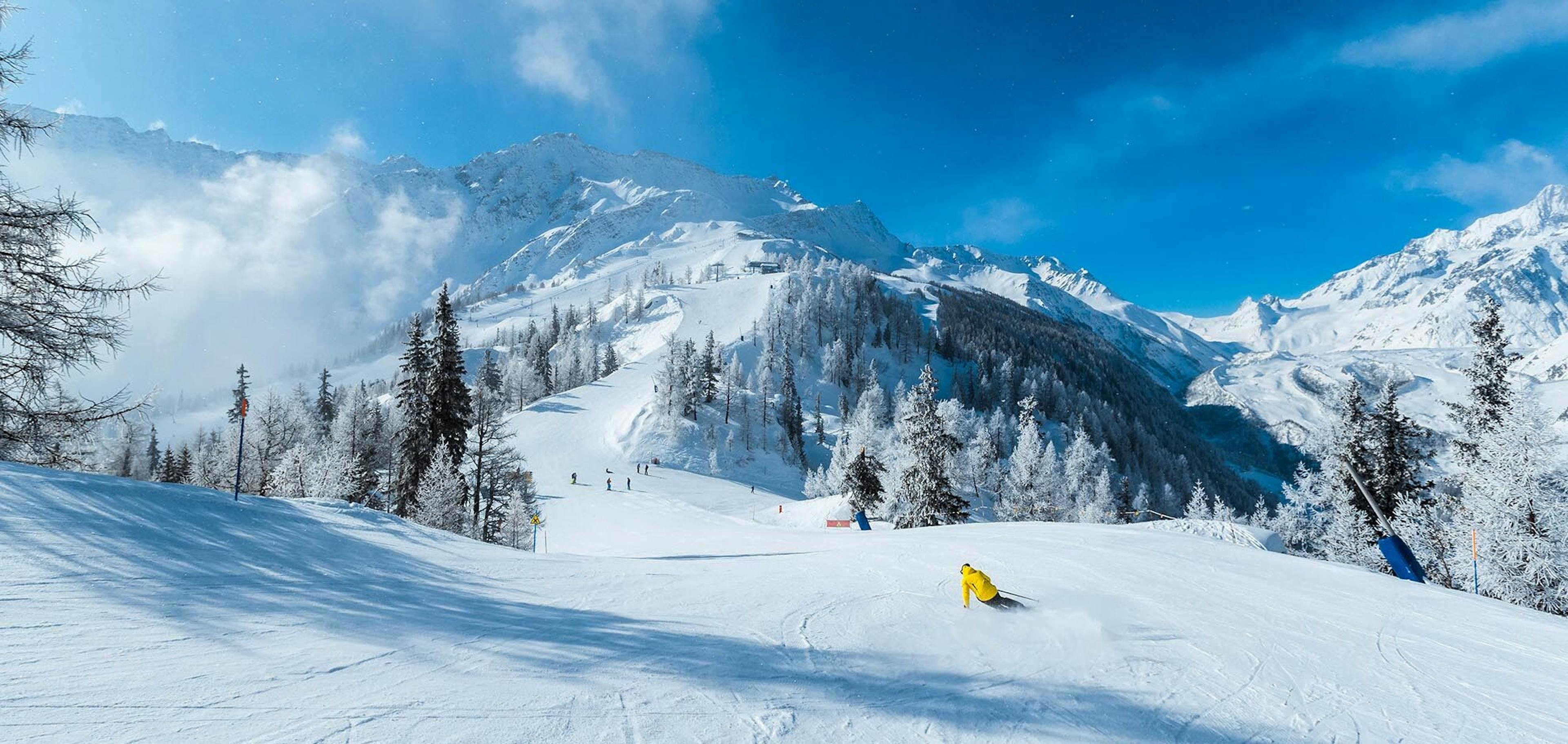 Skier in yellow jacket skiing the slopes of Courmayeur, Italy