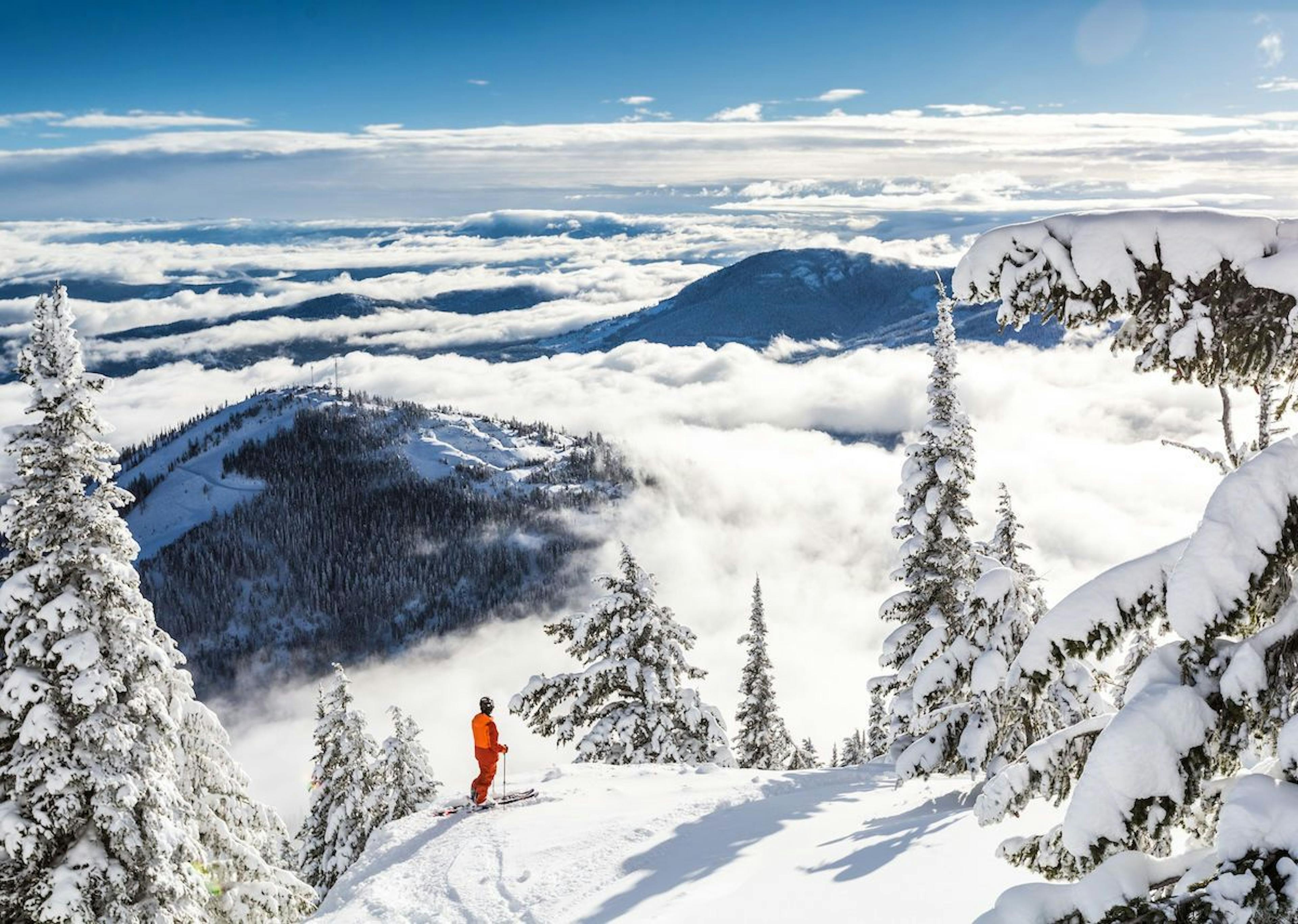 Skier in orange jumpsuit observing the fog at RED Mountain Resort