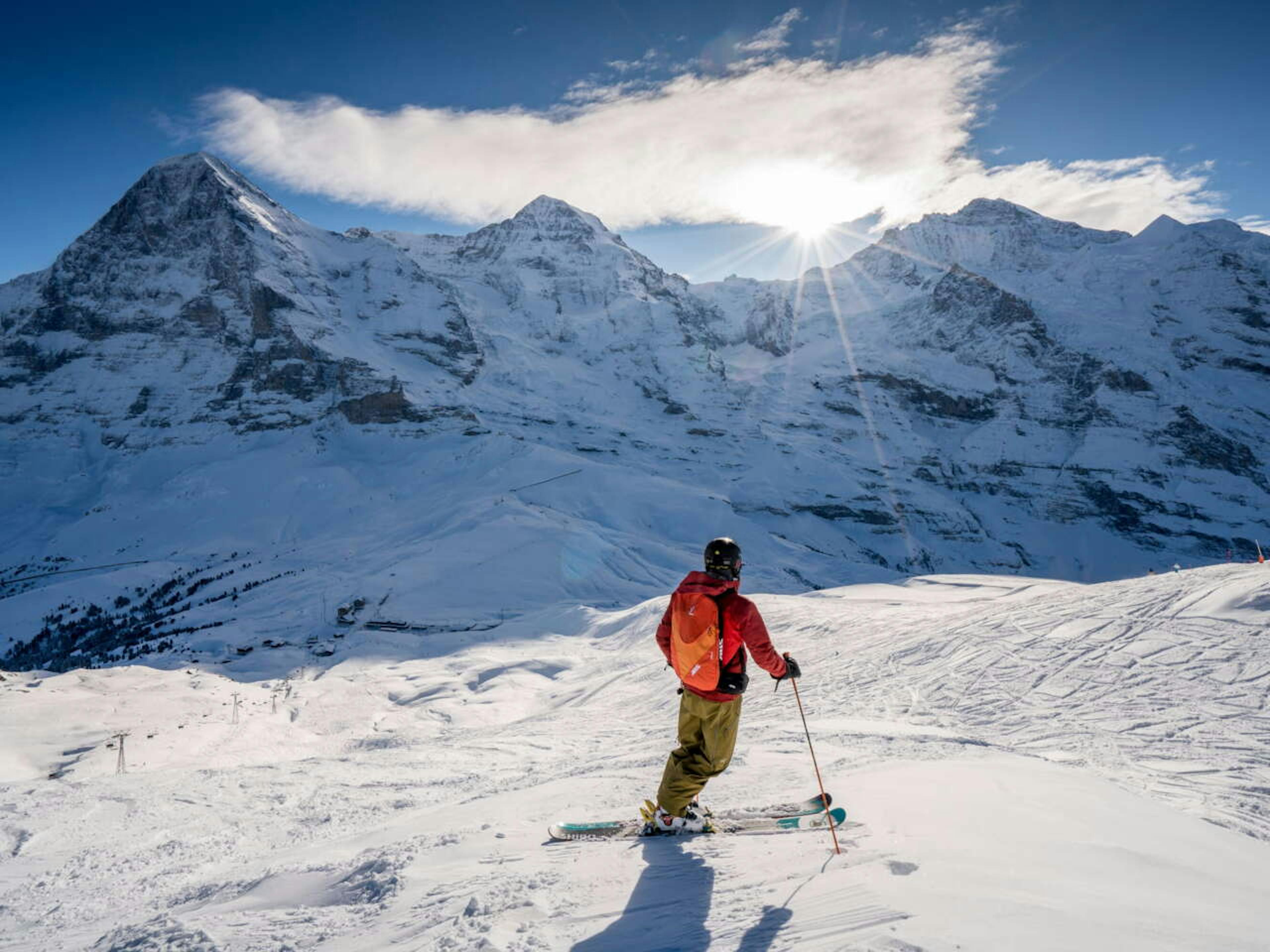 Man in orange ski jacket gazing at the horizon at Grindelwald