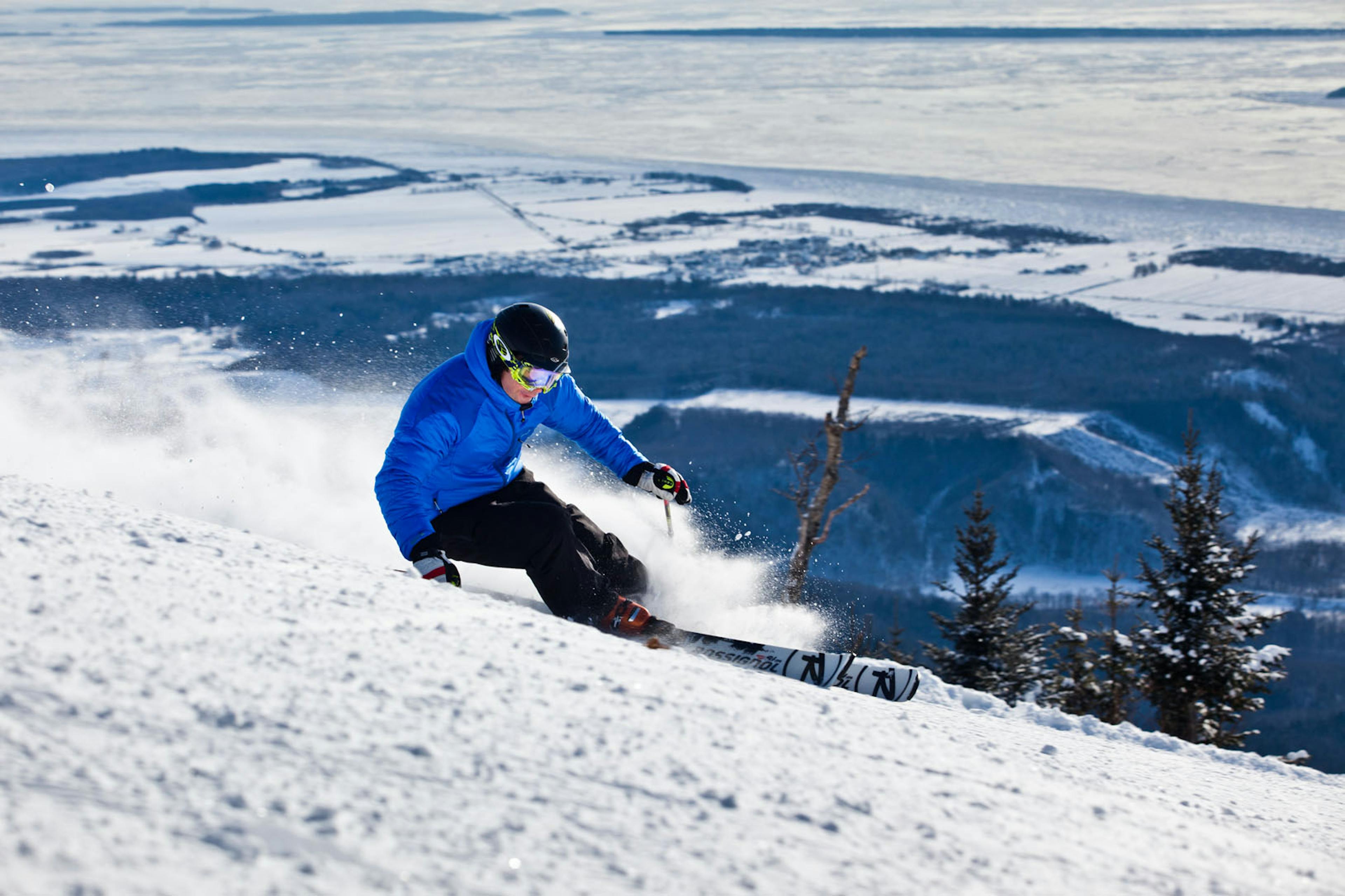 Skier in blue jacket skiing down the slopes of Mont Sainte-Anne