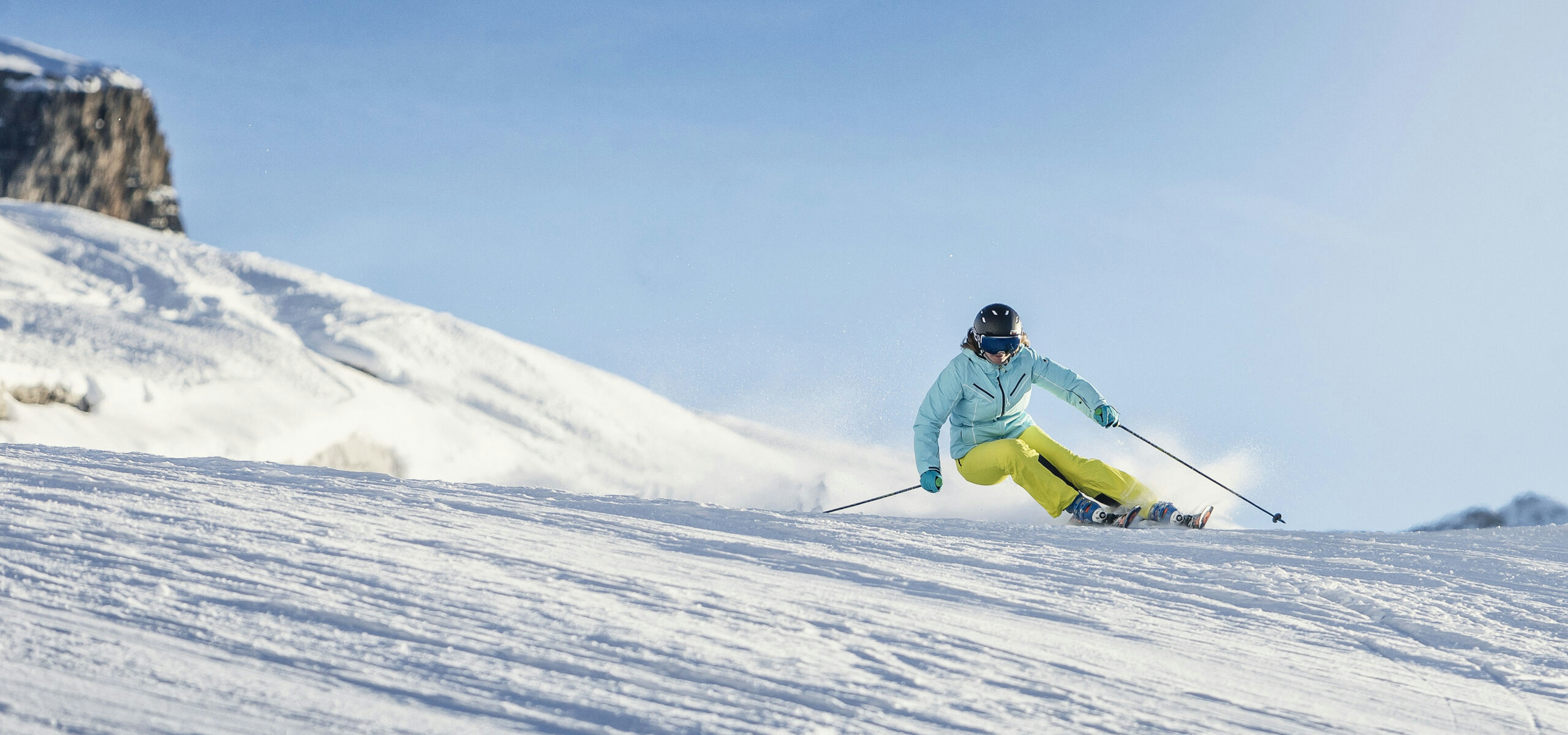 Female skier in yellow ski pants hitting the slopes at Madonna di Campiglio in Italy