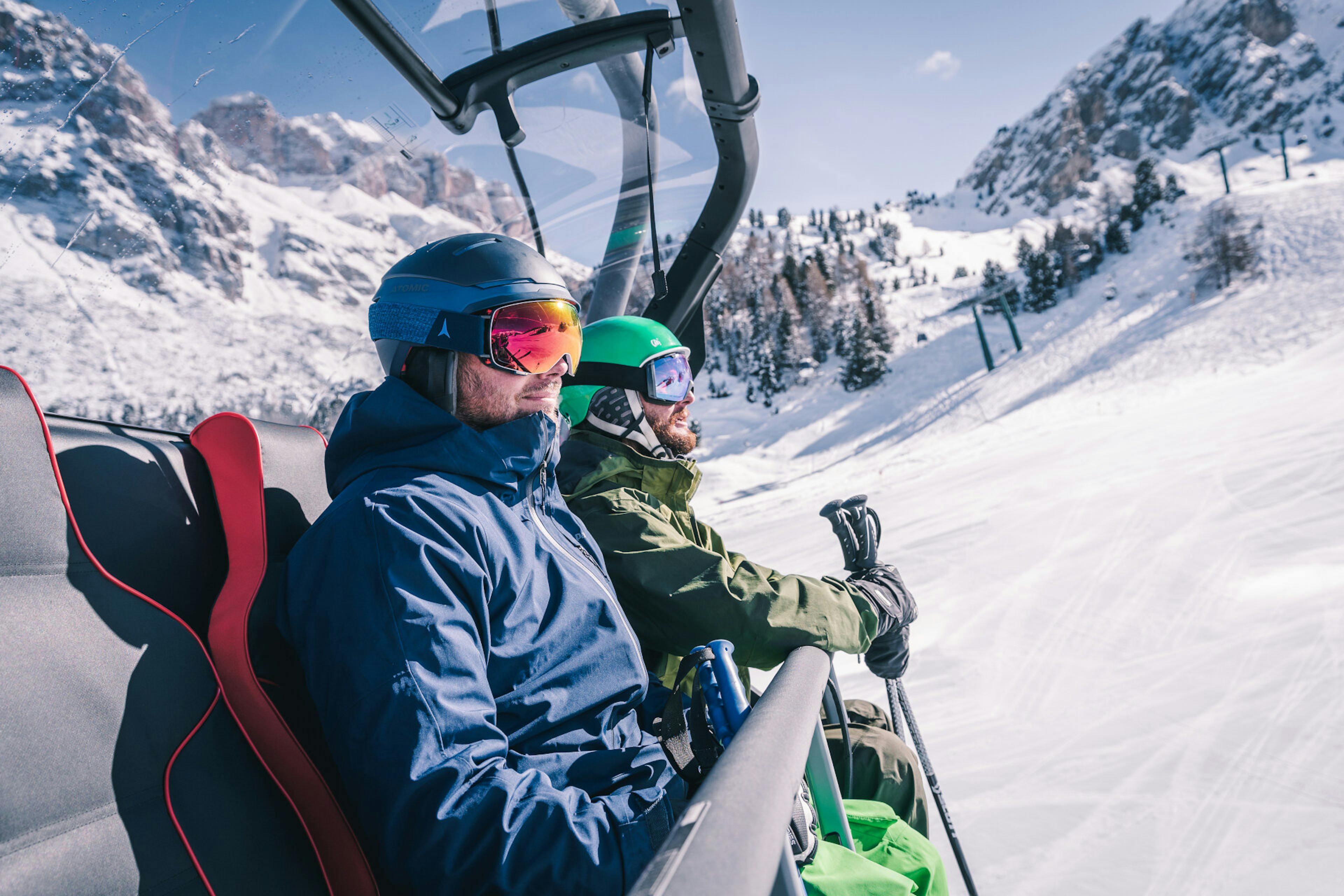 Two skiiers riding the chairlift in Val di Fassa in Italy