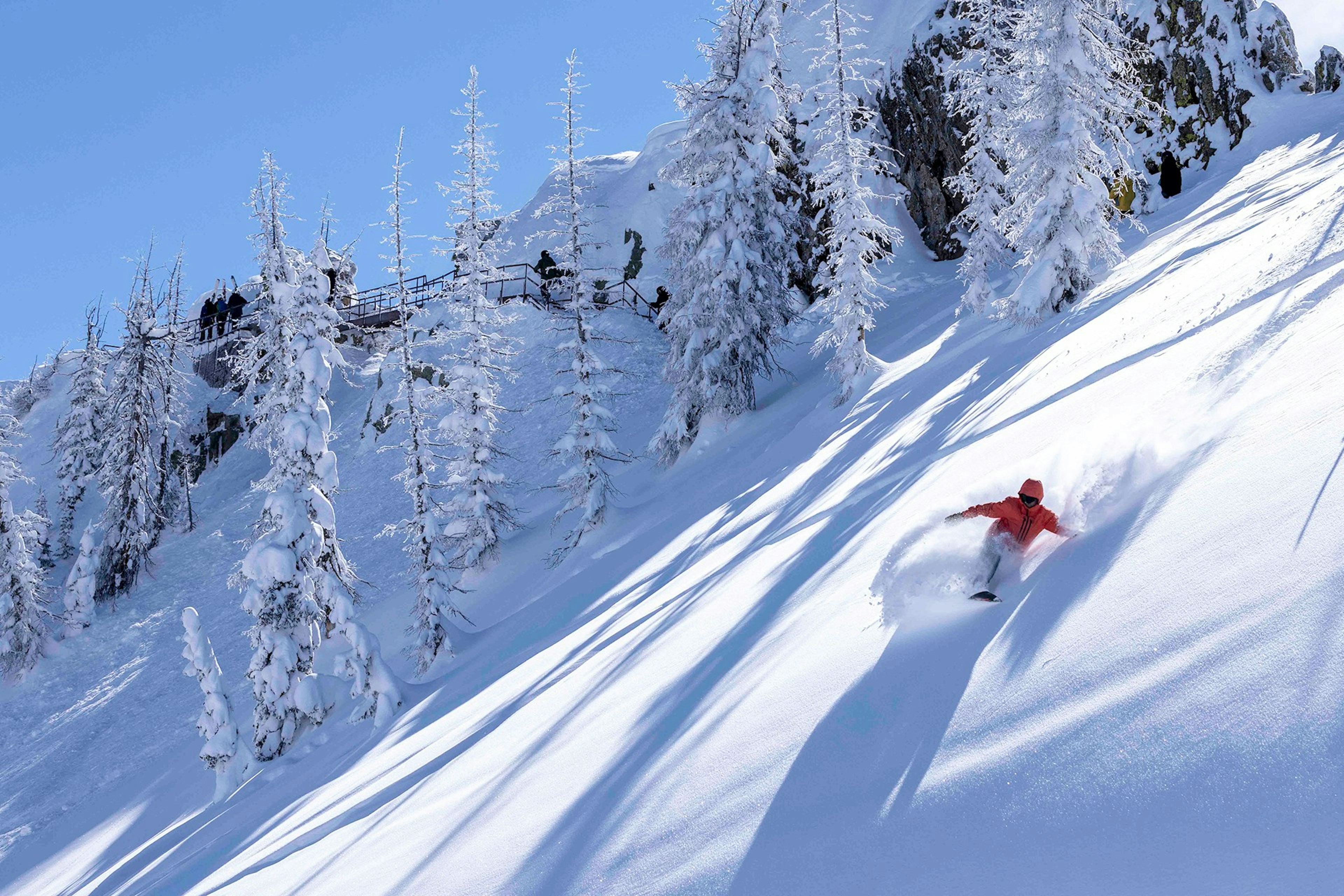 Skier of undiscernible gender in orange ski jacket skiing the slopes of Wolf Creek Ski Area in Colorado, U.S.