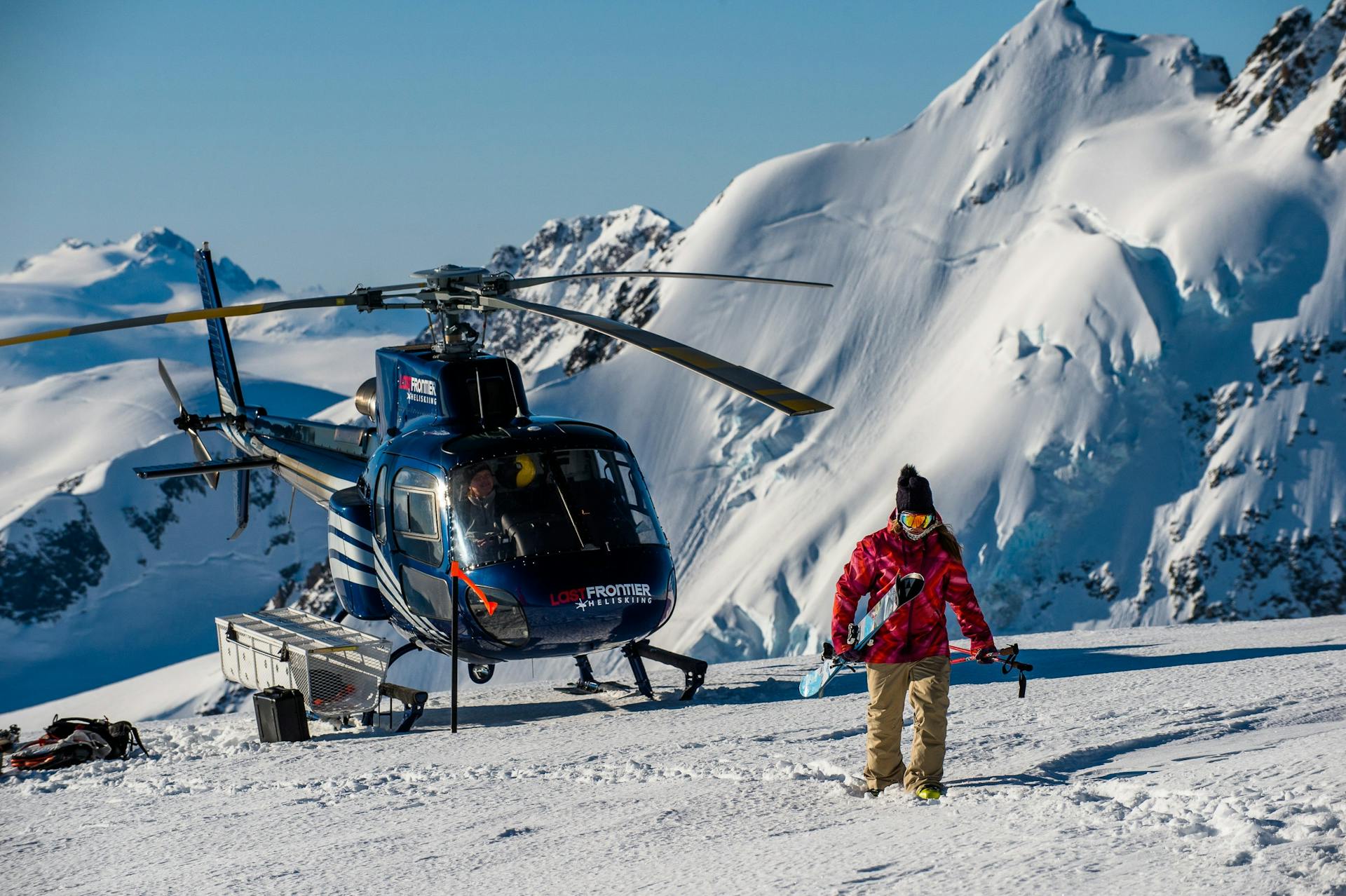 Last Frontier helicopter and heliskier at a mountain summit.