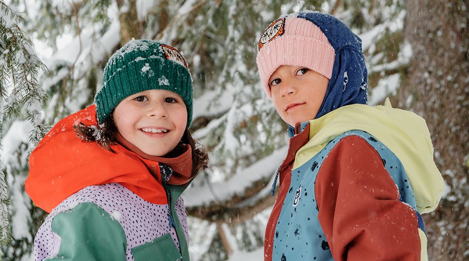 Two children in bright jackets and hats joyfully playing in the snow