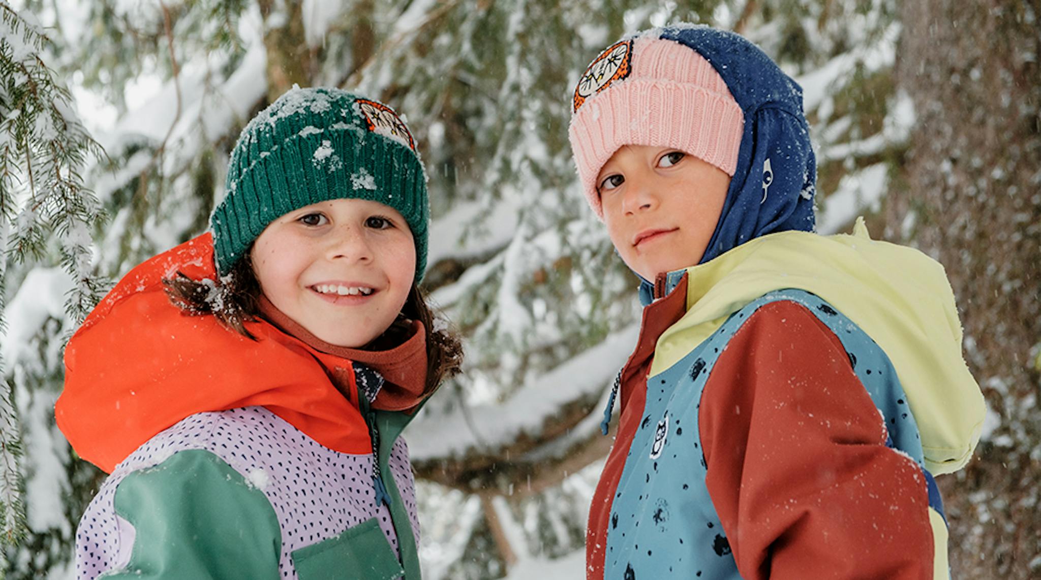 Two children in bright jackets and hats joyfully playing in the snow