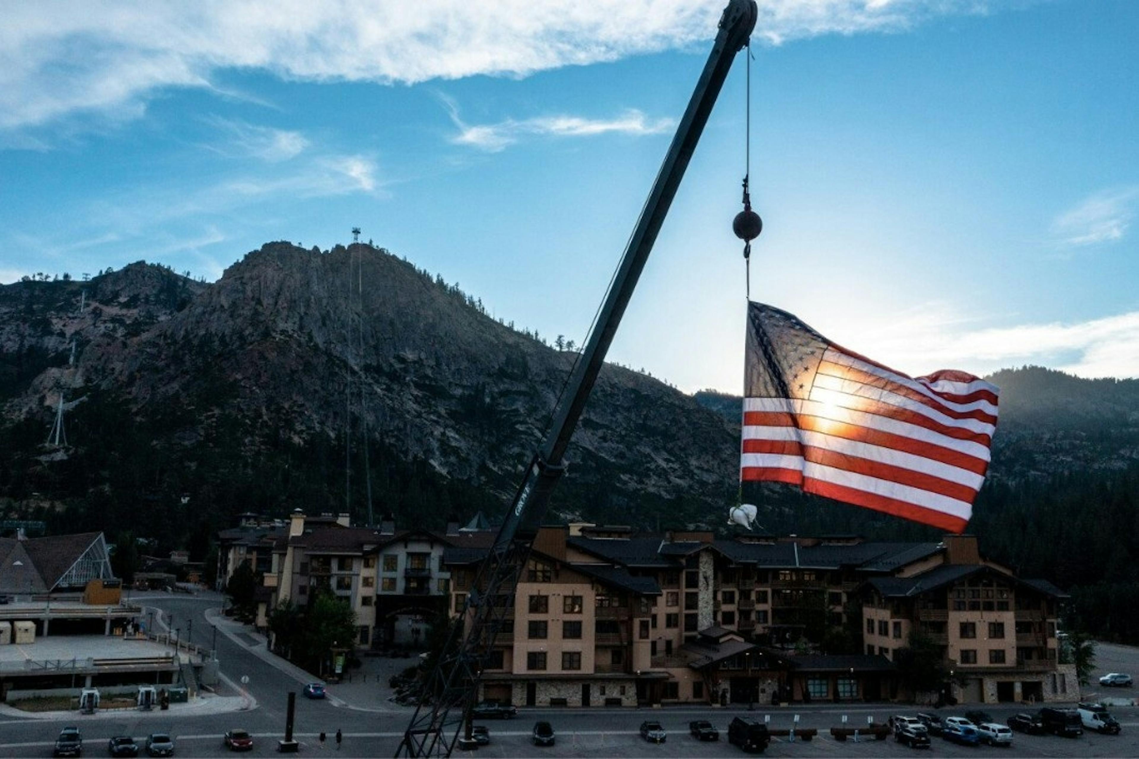 An American flag backlit by the sun flies over the mountain town of Lake Tahoe