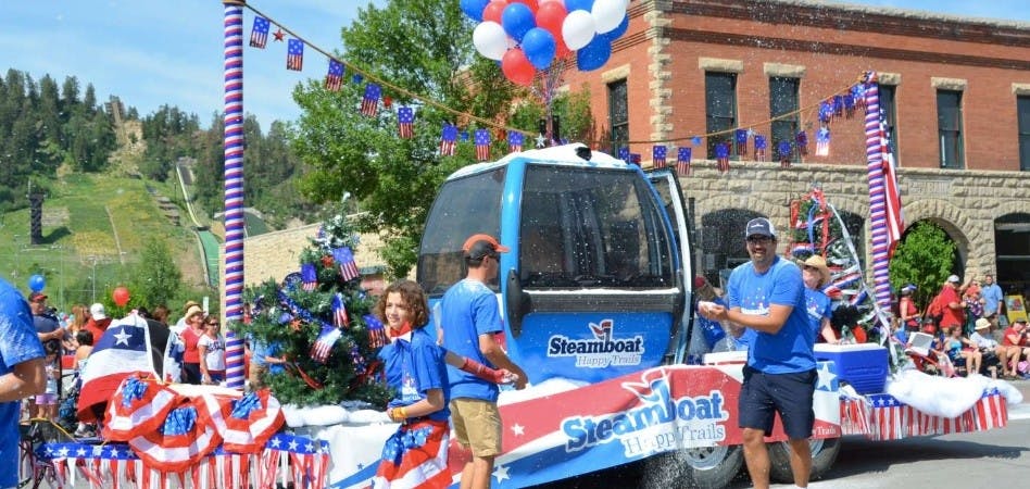 Participants walk in the Steamboat Springs 4th of July parade alongside a Steamboat Ski Resort Gondola float