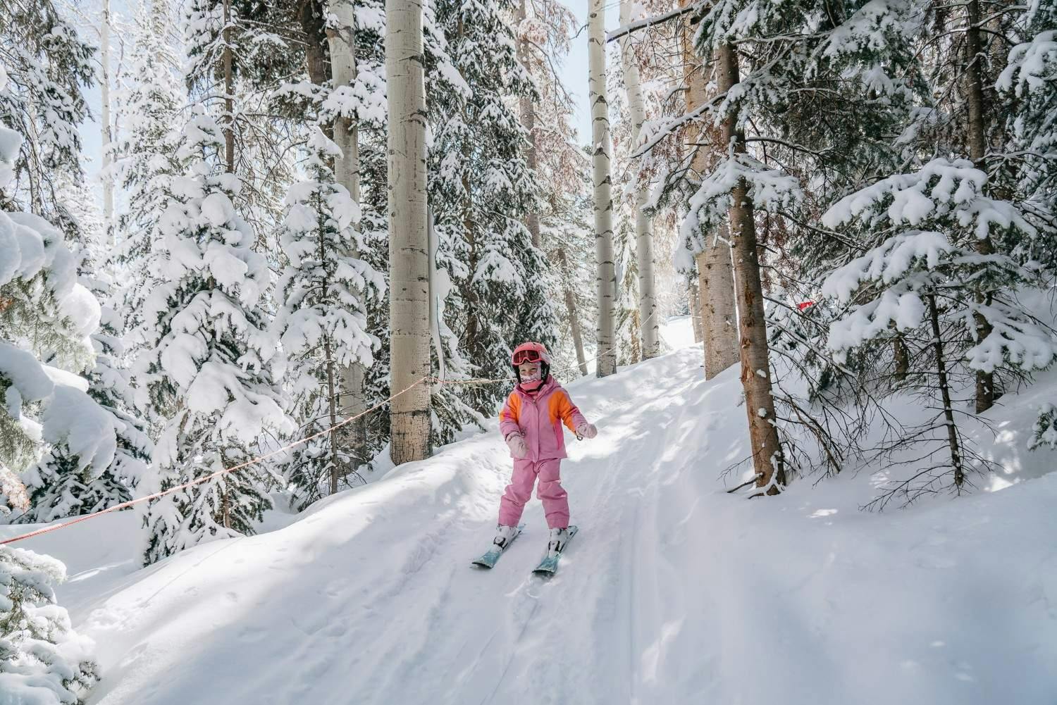 Young skier rides through the snow covered tree trails on a bluebird day at Aspen Snowmass Ski Resort