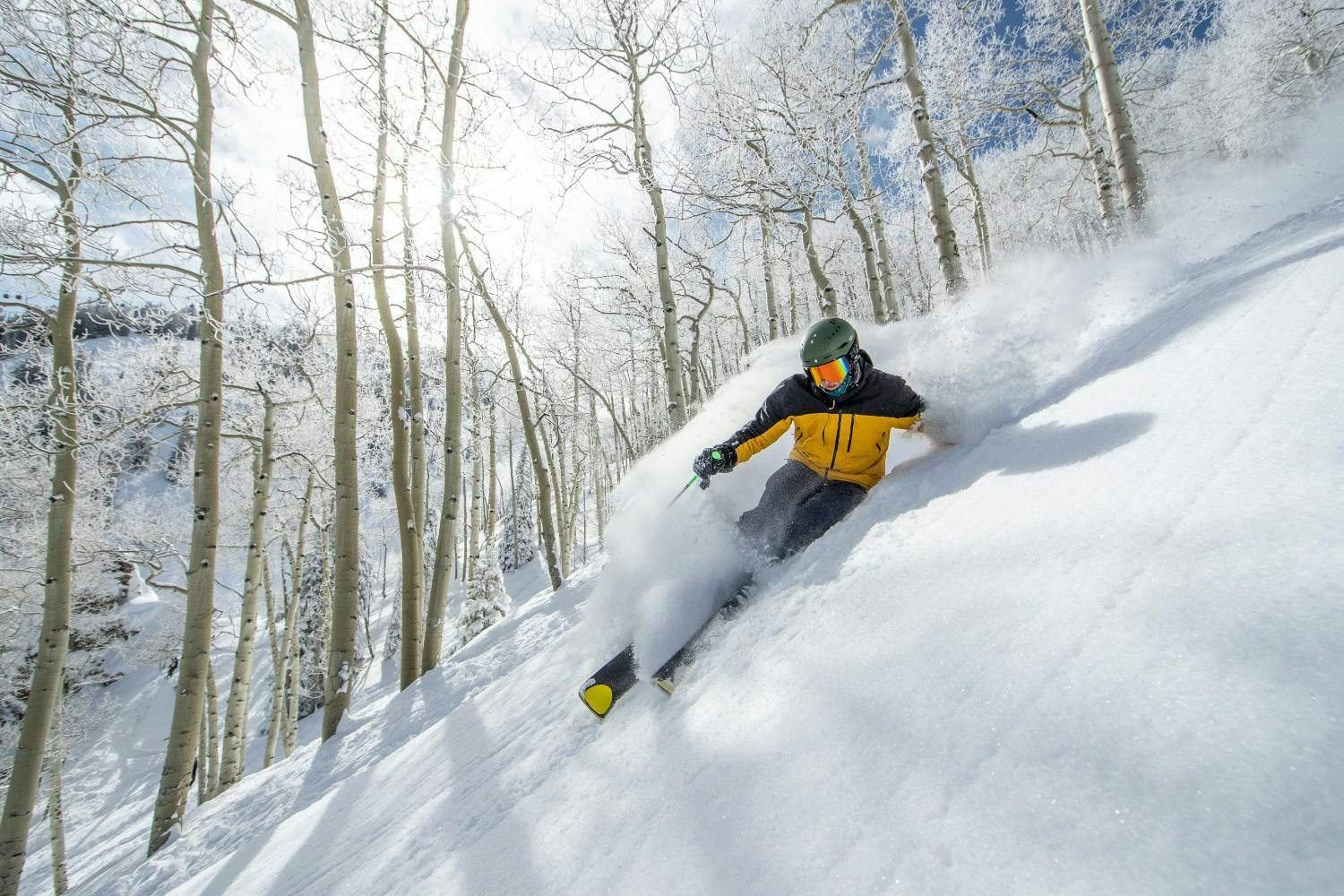 Skier bombs down a steep run at Aspen Snowmass on a sunny day