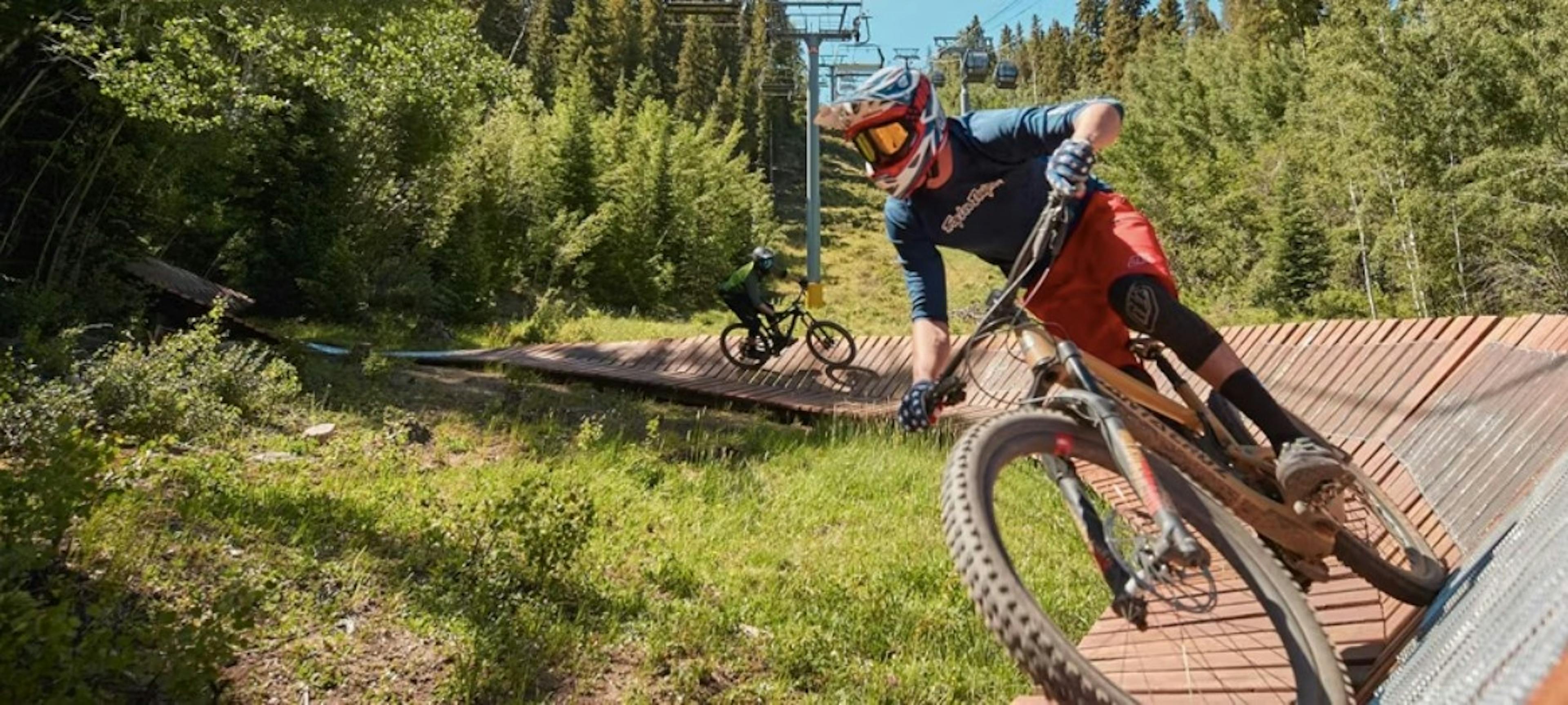 Two mountain bikers riding a wood feature at Keystone Bike Park