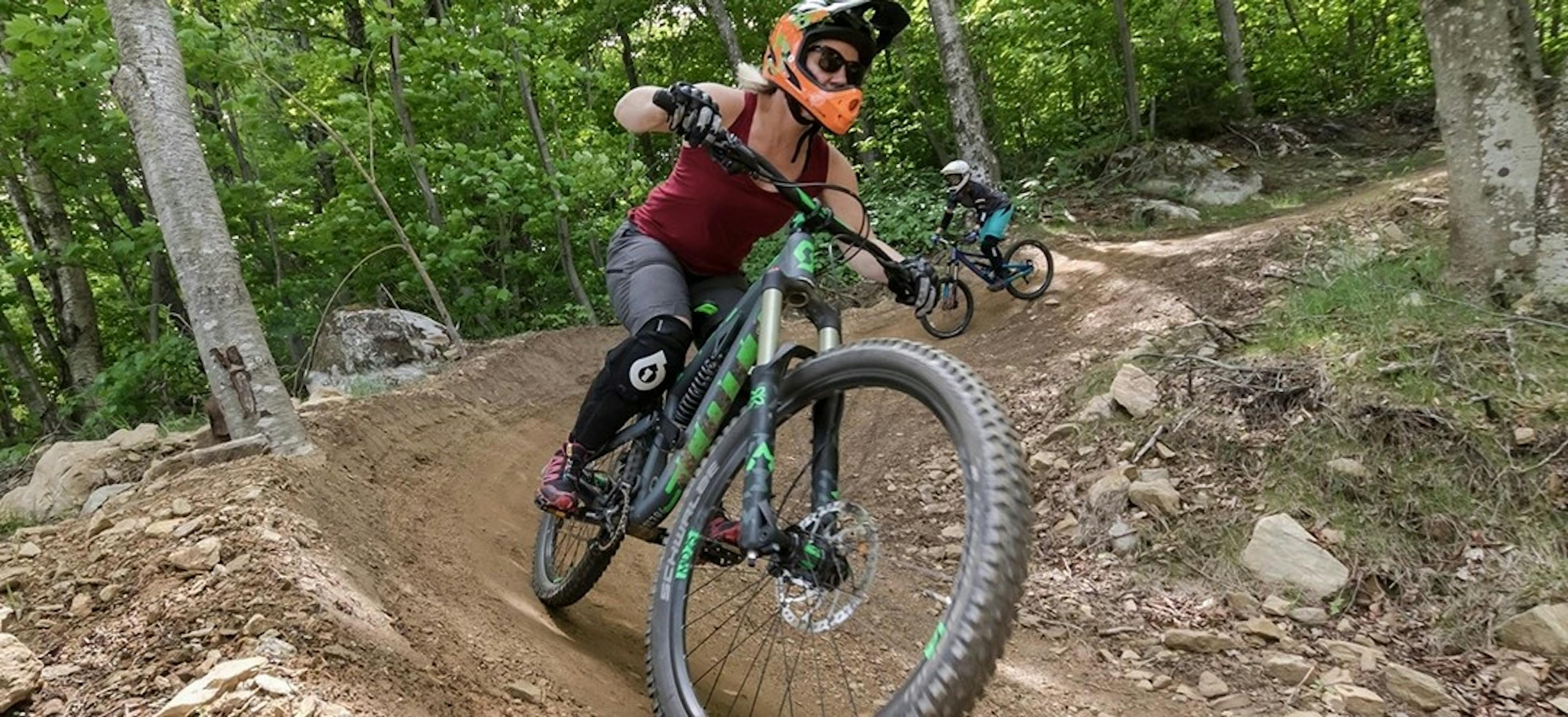 Two mountain bikers take a turn on a downhill trail at Killington Mountain Bike Park