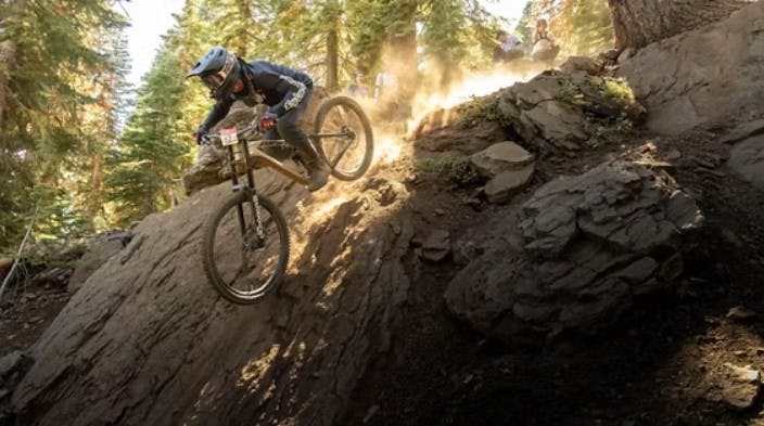 A mountain biker descends a steep rock cliff at Northstar Bike Park