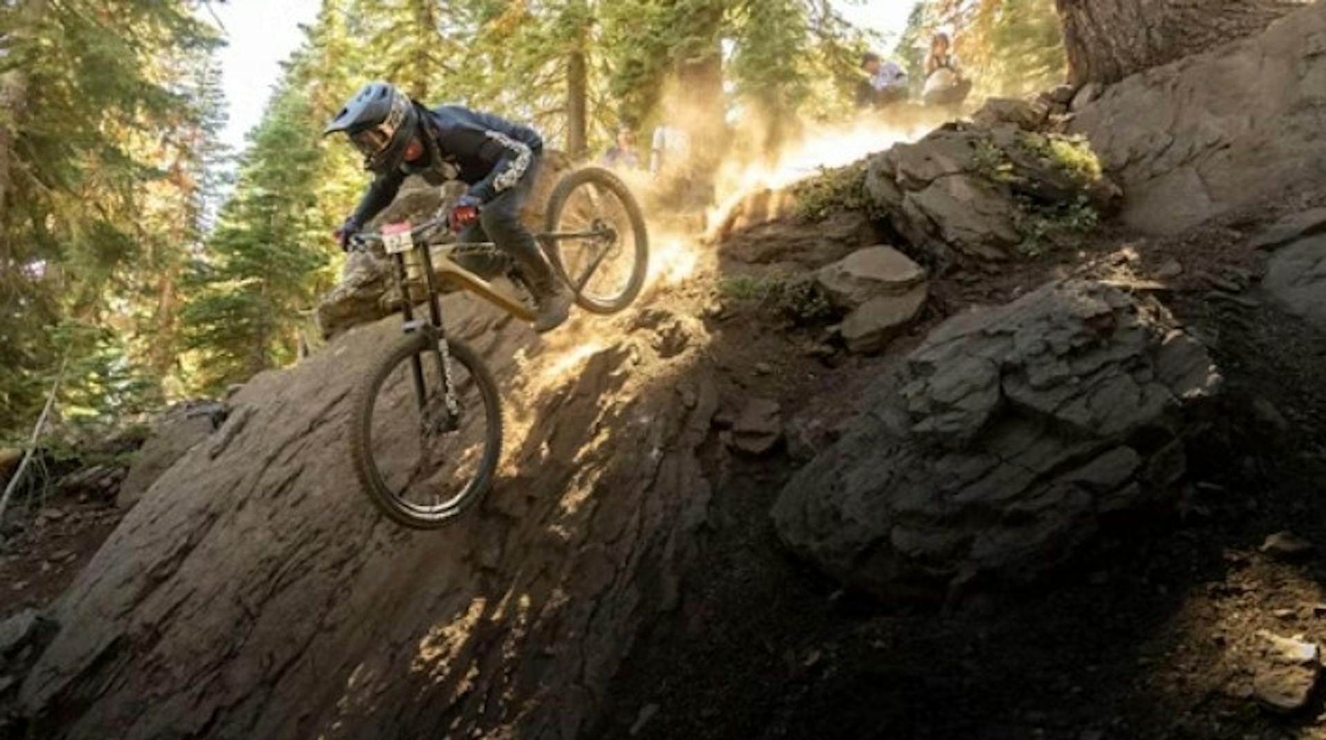 A mountain biker descends a steep rock cliff at Northstar Bike Park