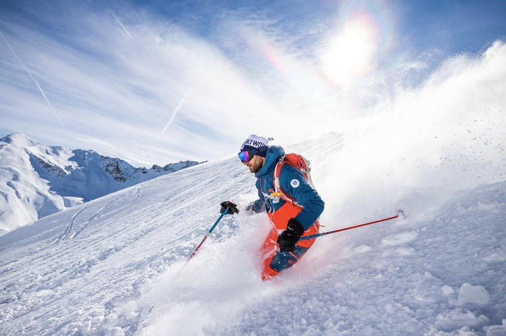 A skier knee-deep in powder skiing down a run at the Courchevel ski resort on a sunny day