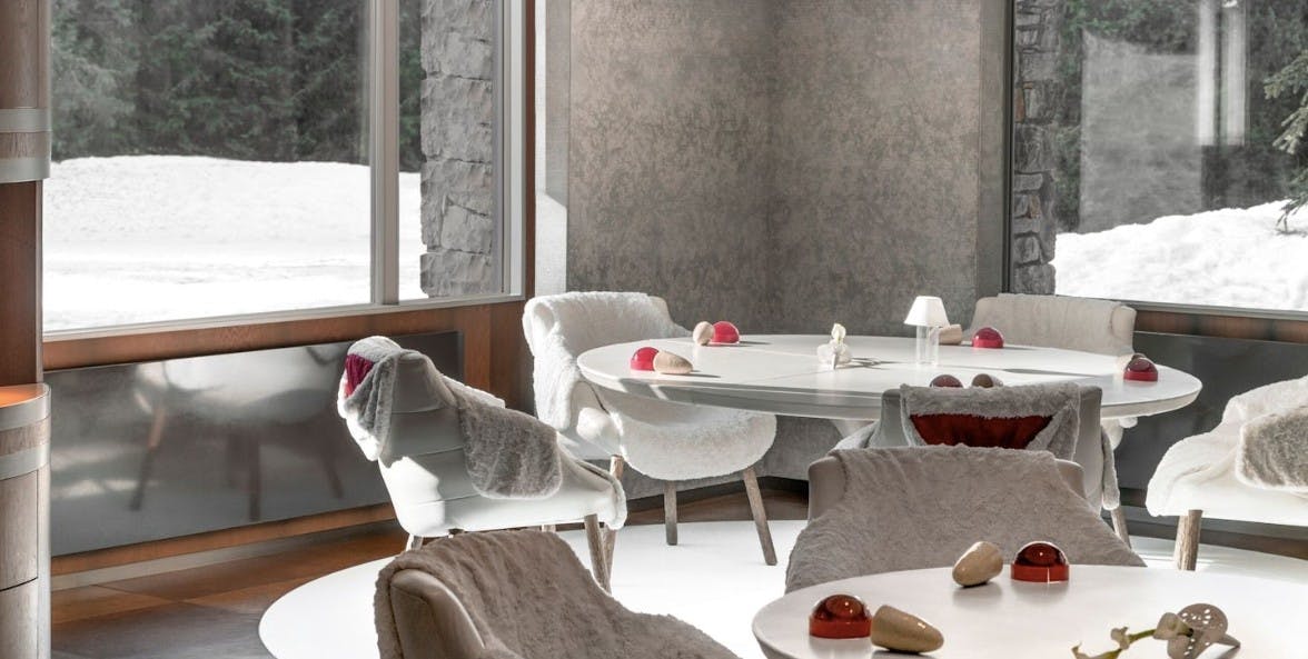 Modern white chairs surround white tables in the dining room of Le 1947 à Cheval Blanc