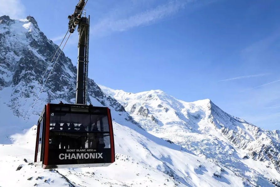 The Aiguille du Midi cable car gliding by with a snowy alpine mountain backdrop of the Swiss Alps