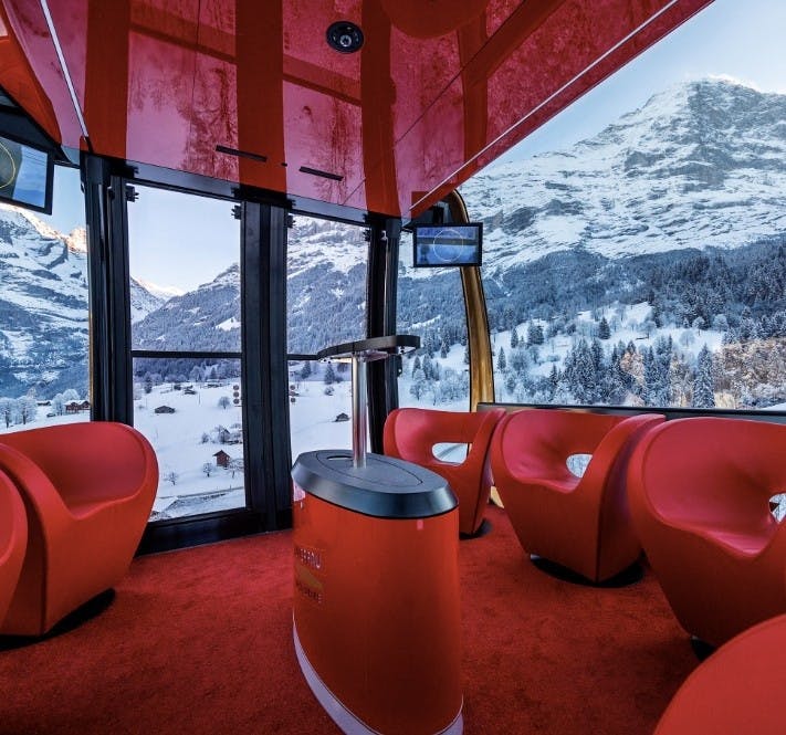 Inside the Eiger Express VIP Gondola showcases red velvet carpet, seats, panaromic glass windows, TVs, and a soundsystem