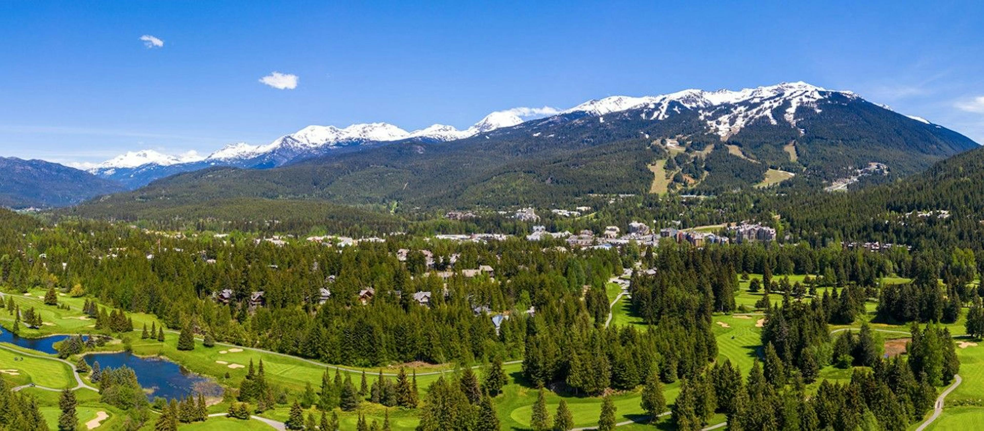 Aerial view of Whistler Golf Club course with Whistler Blackcomb snow-tipped mountains in the distance