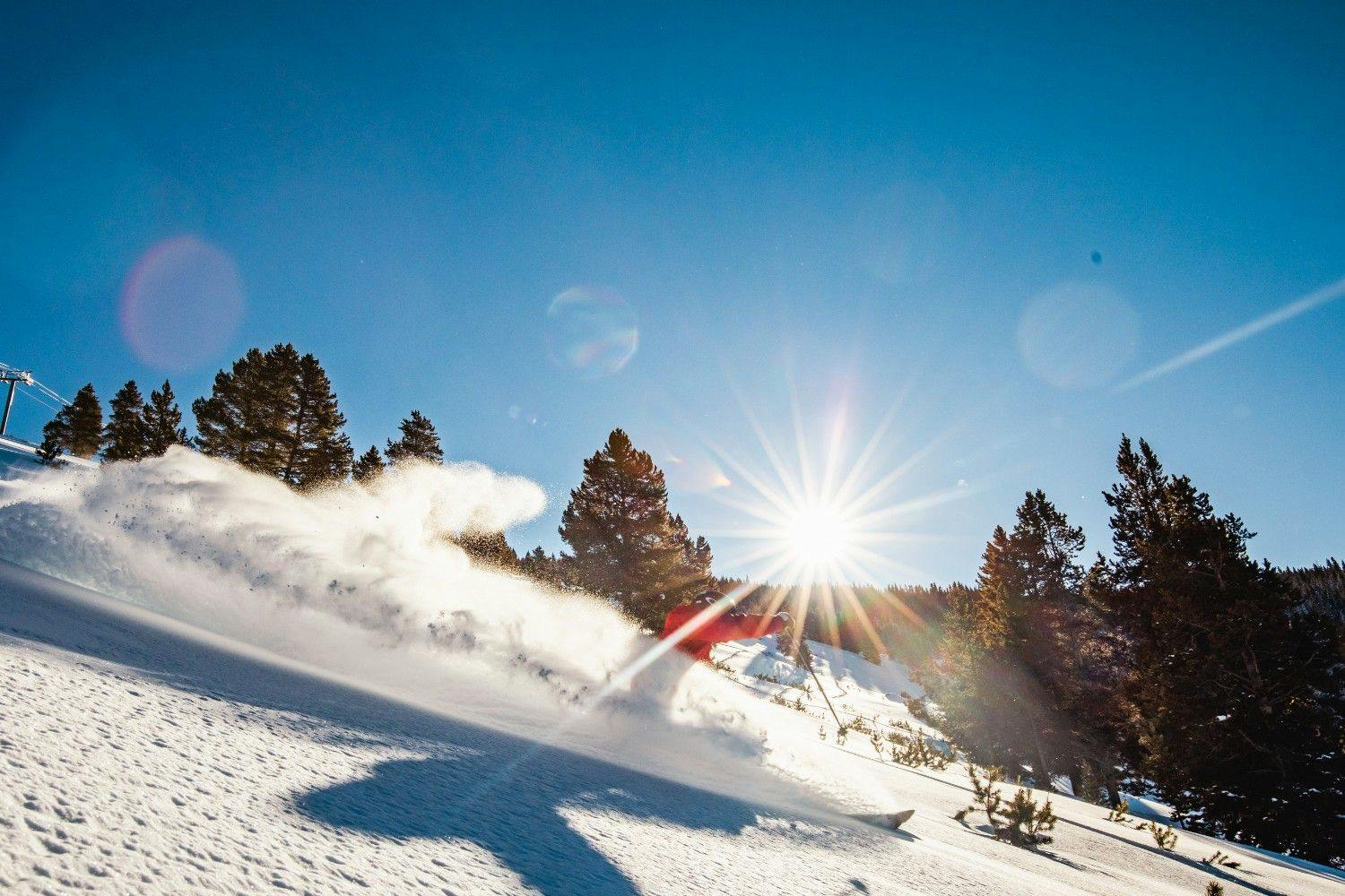 Skier spraying powder on a run at Vail Resort on a bluebird day