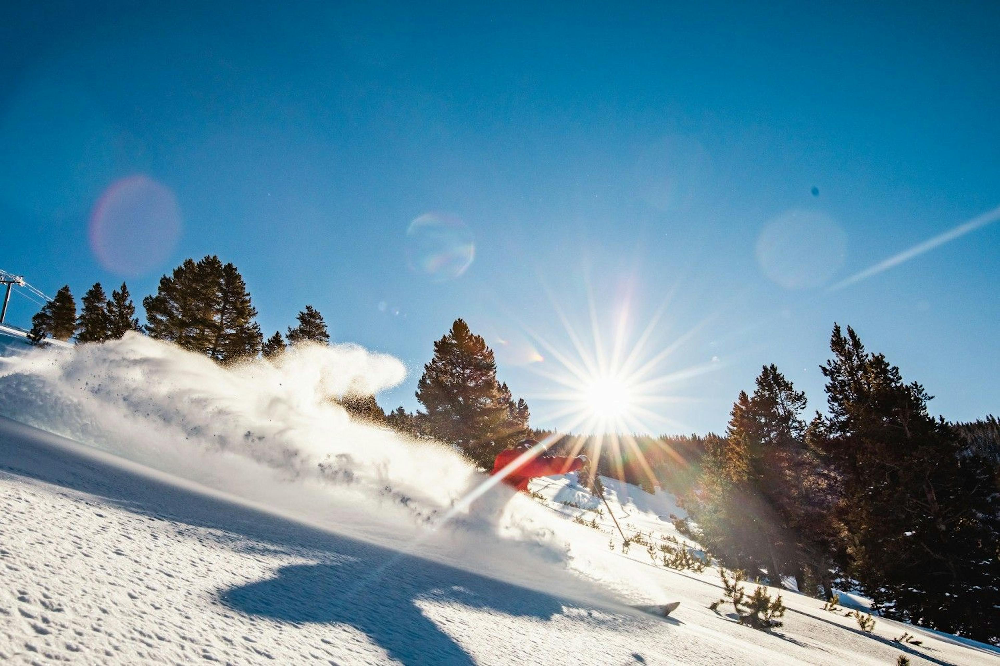 Skier spraying powder on a run at Vail Resort on a bluebird day
