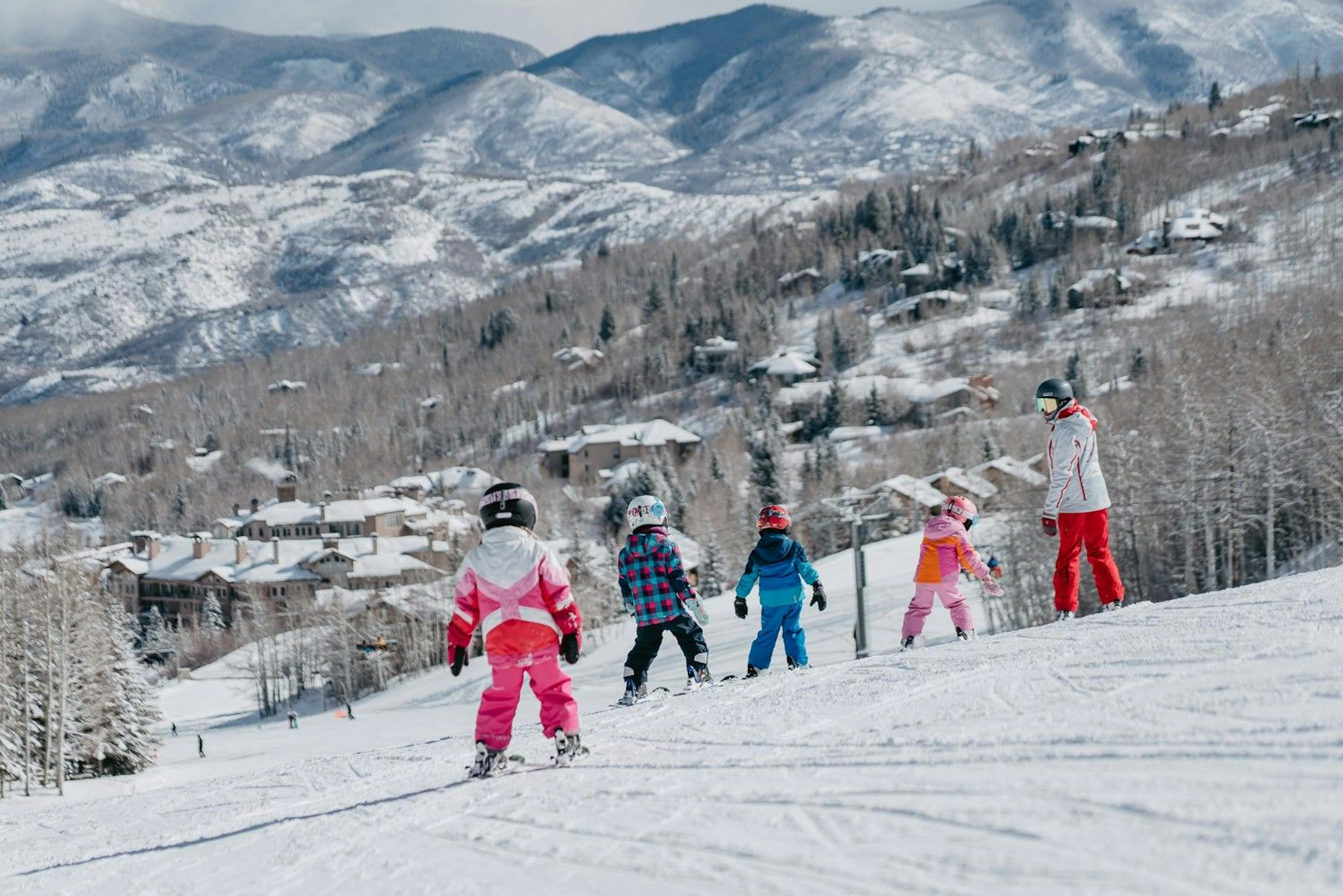 Aspen ski instructor with 4 kids on skis on the snowy slopes of Aspen Snowmass Ski Resort