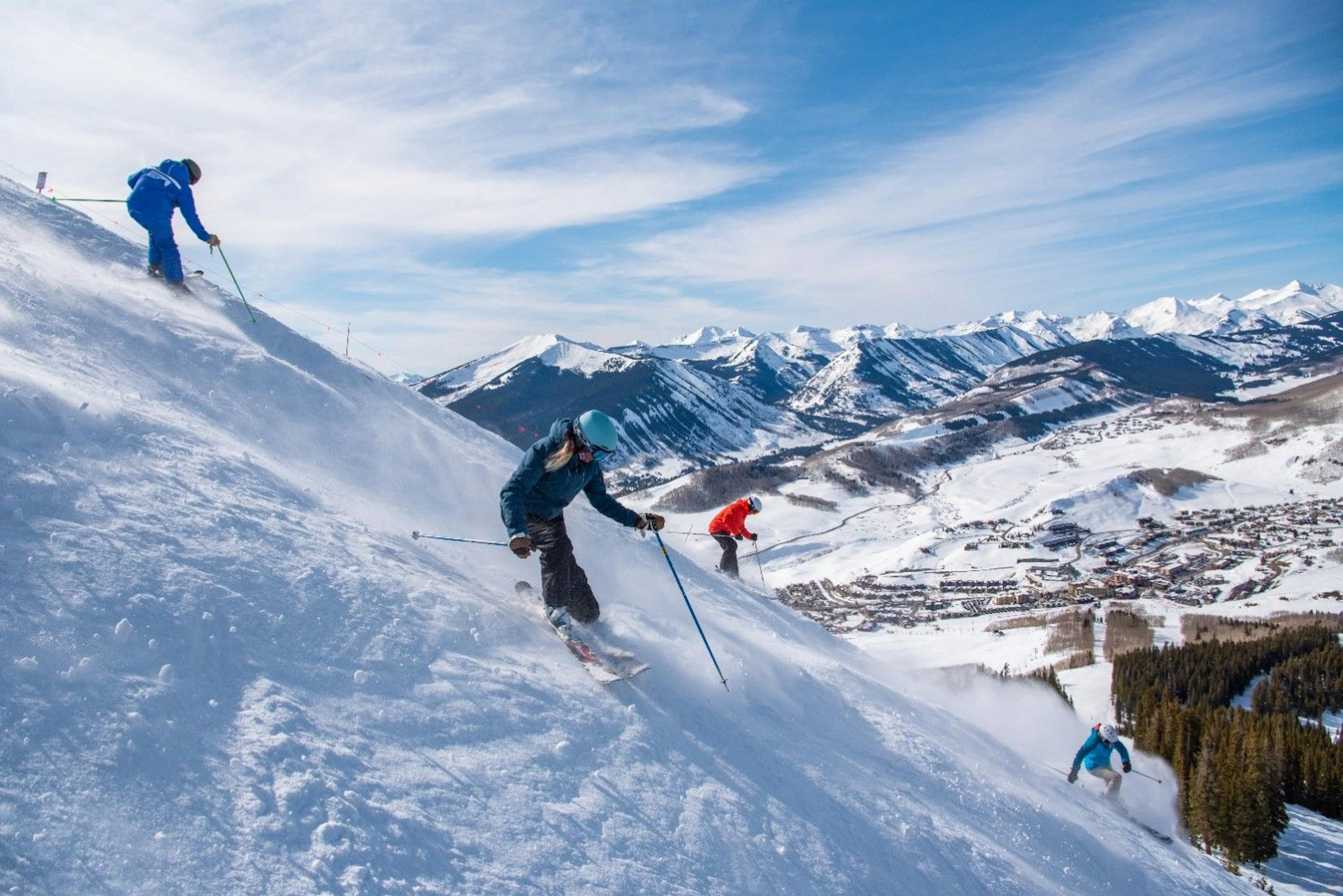 A Crested Butte ski school instructor teaches 3 adult skiers how to get down a steep slope at Crested Butte Resort