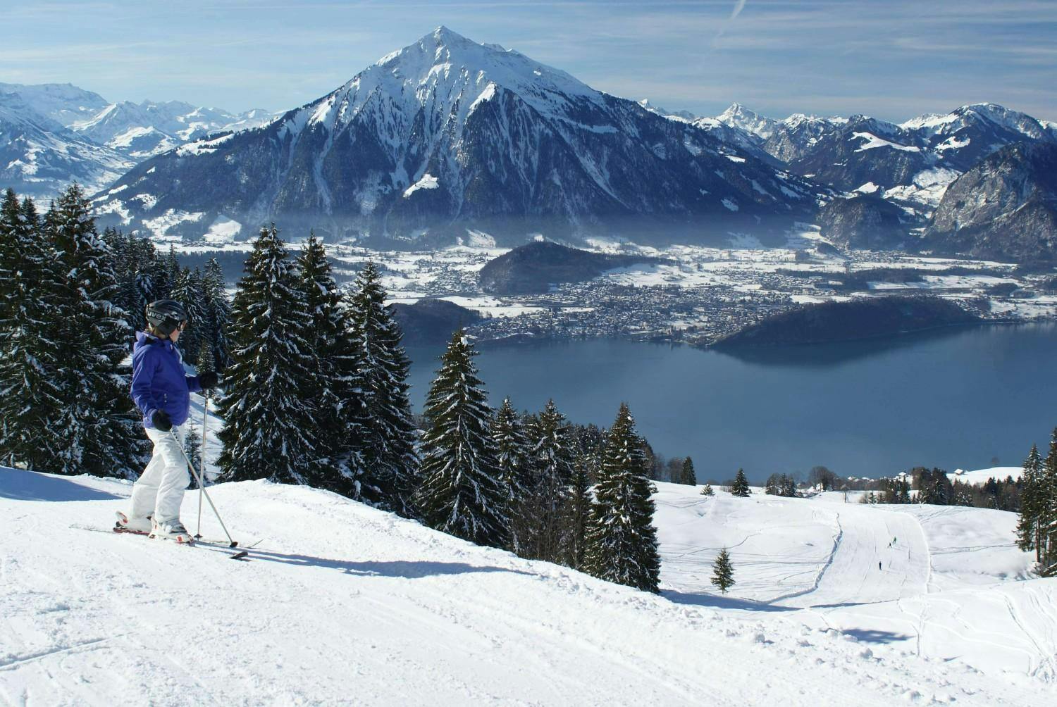 Skier in blue ski jacket gazing at the slopes near Interlaken in the Jungfrau region of Switzerland.