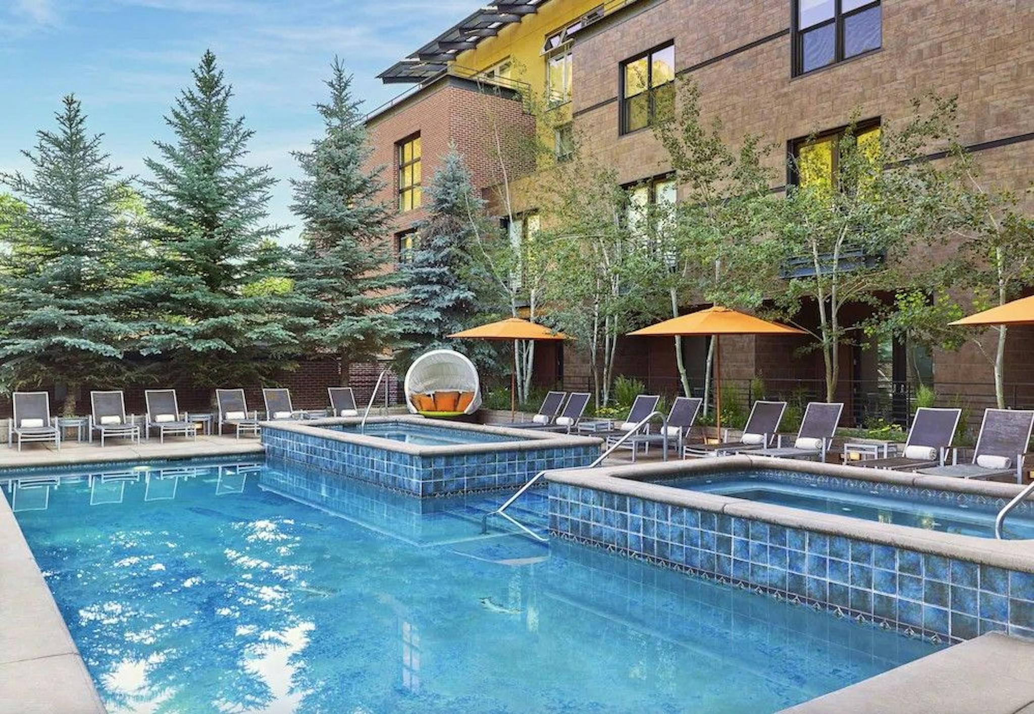The outdoor pool and spa surrounded by lounge chairs and pine trees at the Limelight Hotel