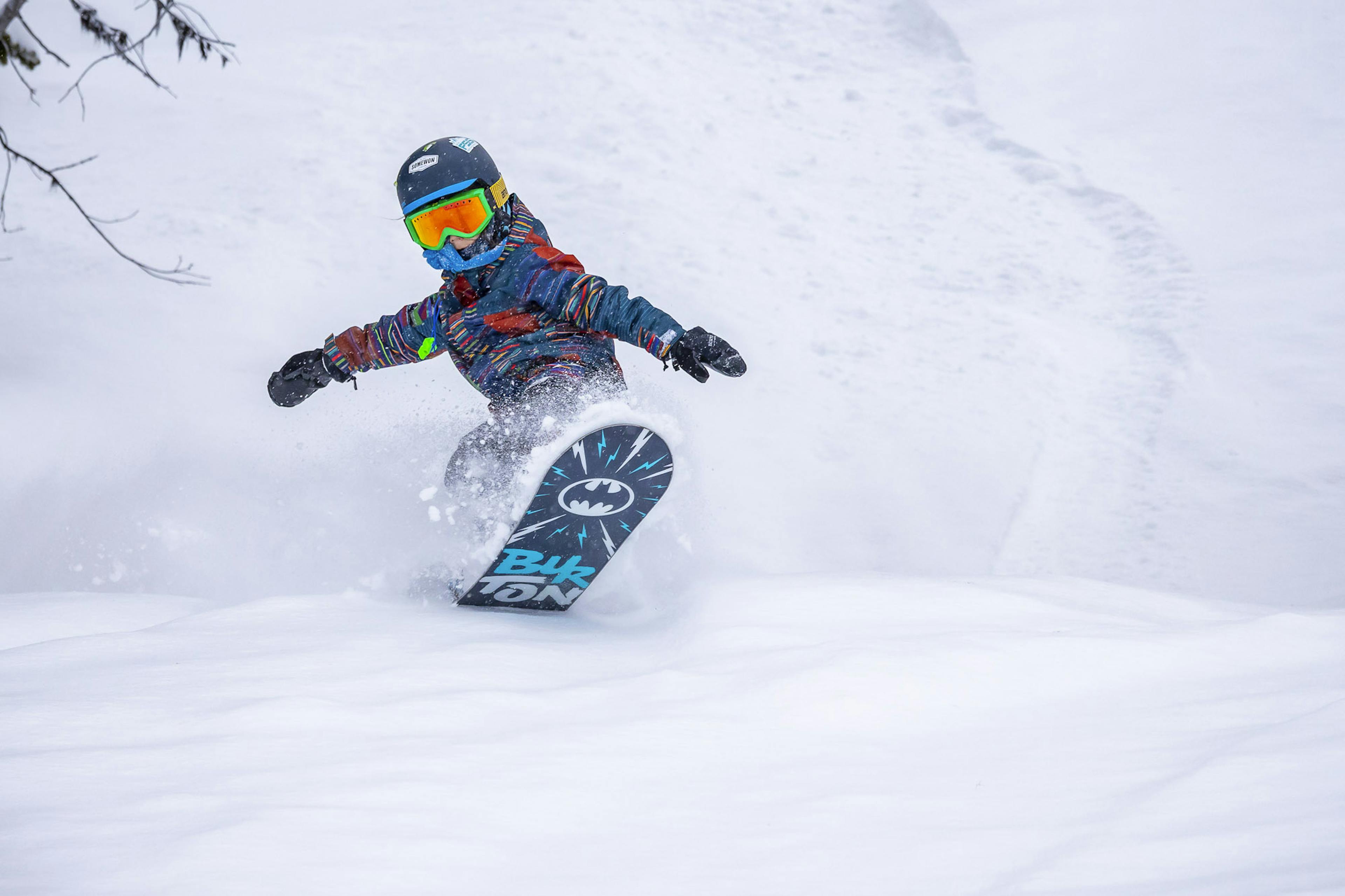 Young kid snowboarding in powder at Revelstoke Resort in Canada
