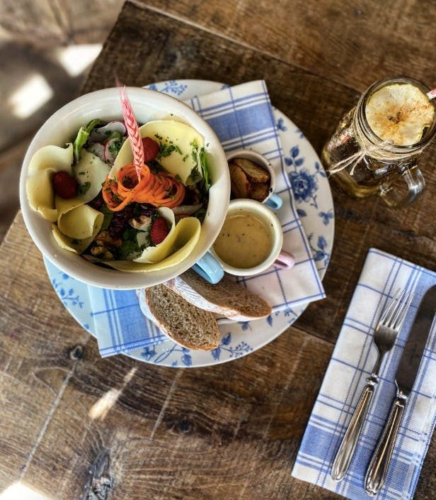 A delicious bowl of food and drink sits on a wooden table at Alpenrose restaurant