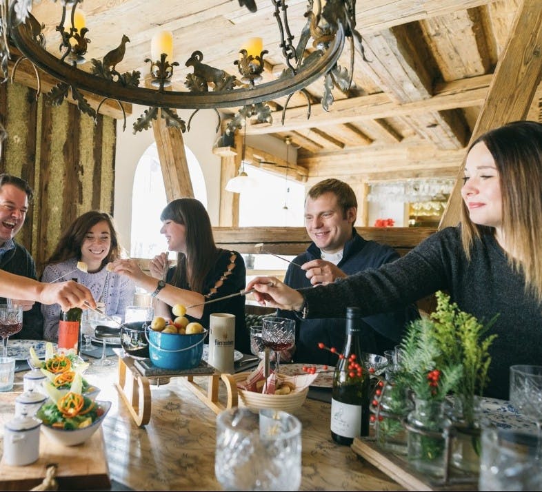 A group enjoys fondue and wine inside at Alpenrose restaurant