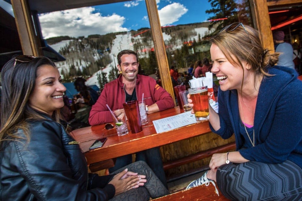 Three friends sitting outside drinking and laughing on the patio at Garfinkel’s