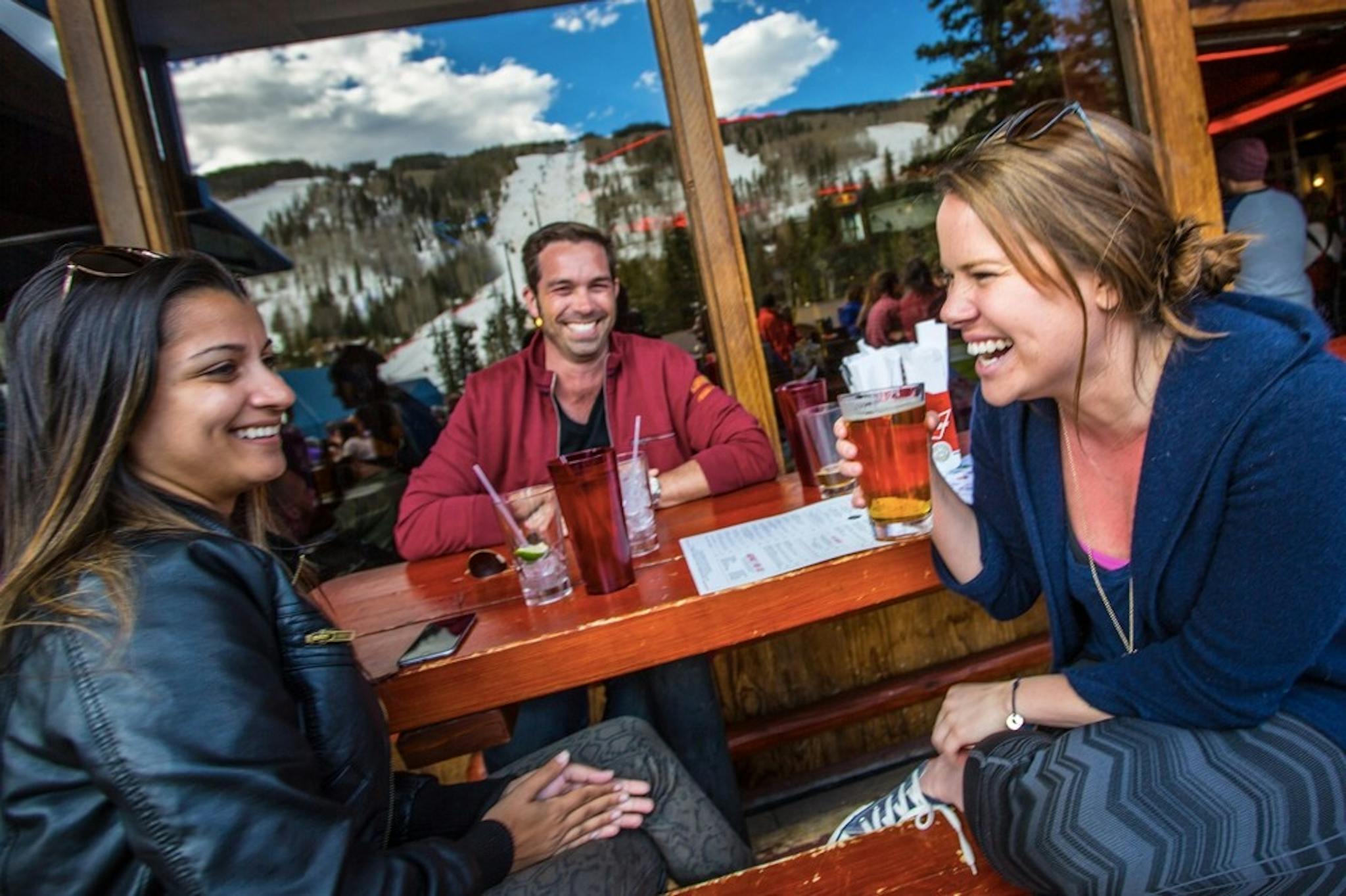 Three friends sitting outside drinking and laughing on the patio at Garfinkel’s