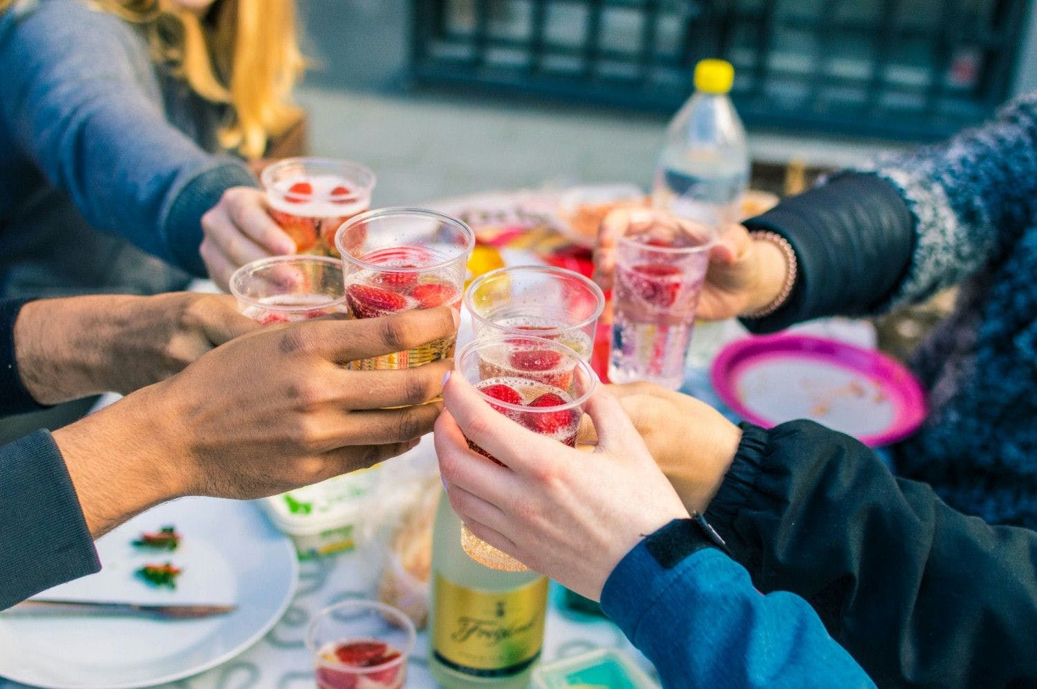 group of friend cheers their drinks on a outdoor patio