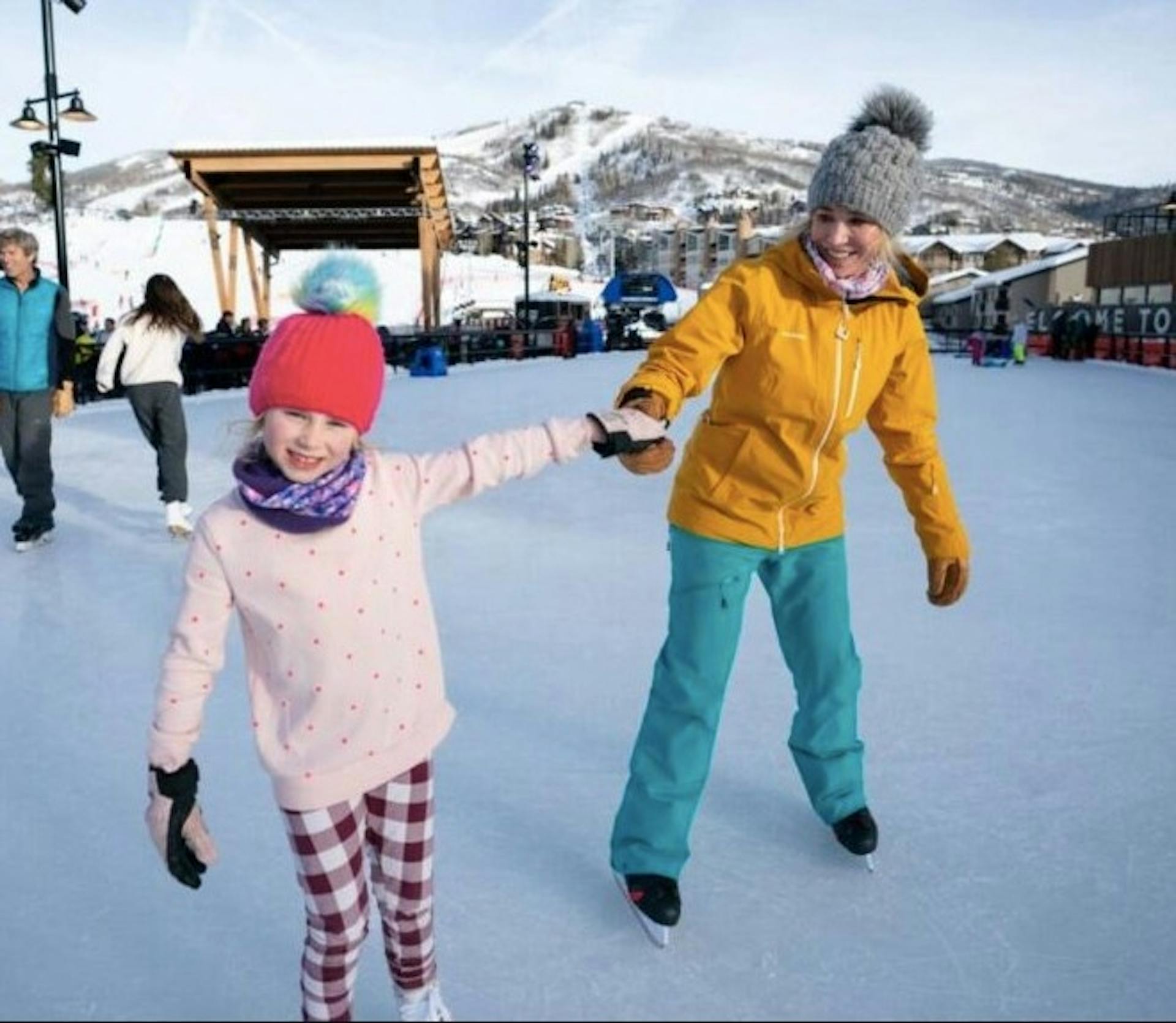 A mom holds hands with her daughter as they ice skate at Streamboat Springs