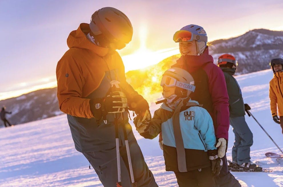 Parents with their kid in ski gear at sunset on the slopes of Streamboat Springs Resort
