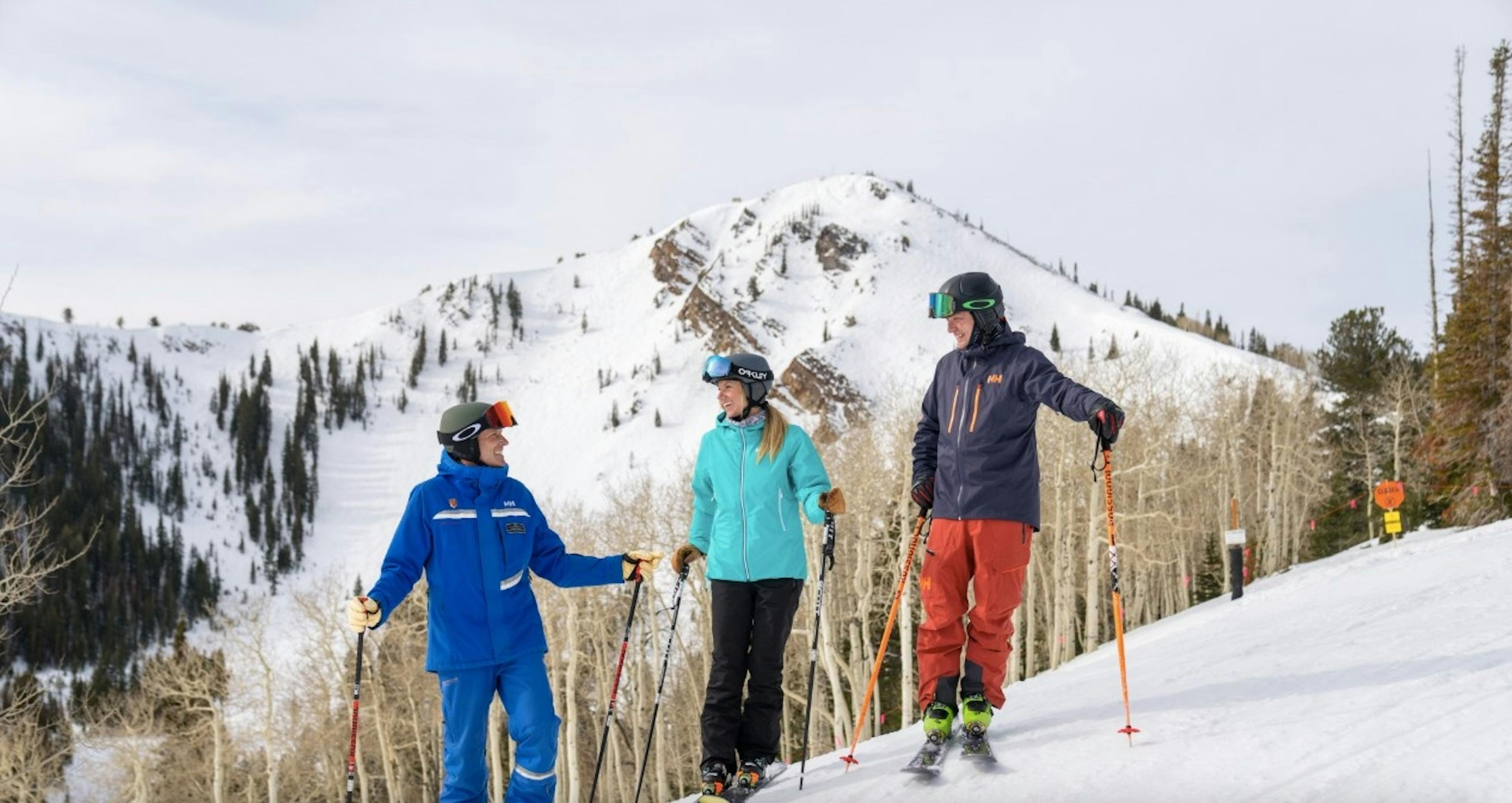 two skiers speak to a ski instructor on the slopes at Park City Resort