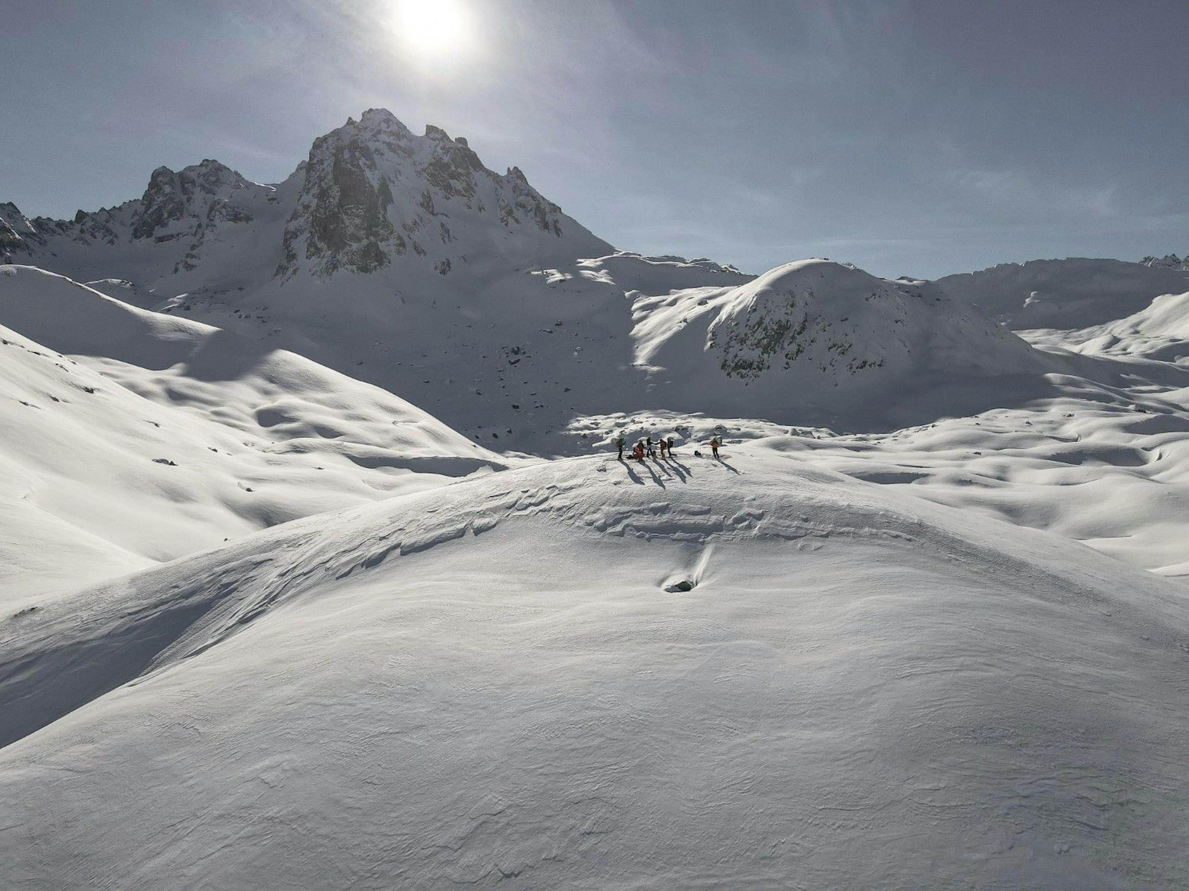 Bird's eye view of a group of skiers standing on a snowy alpine mountain on a sunny day at Courchevel