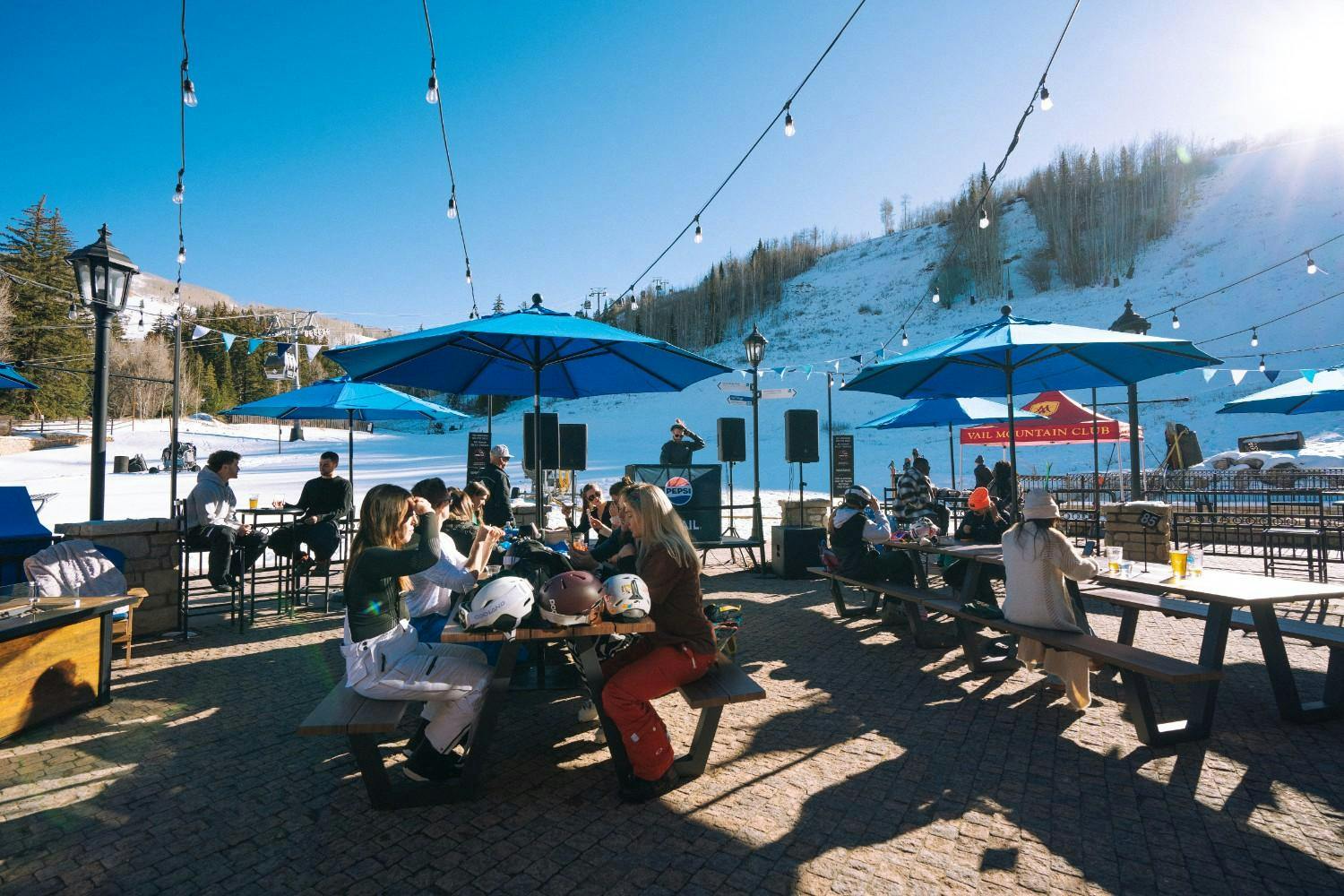 Skiers and snowboarders sit and enjoy the sunny patio at Vail Resort for the Opening Day apres party