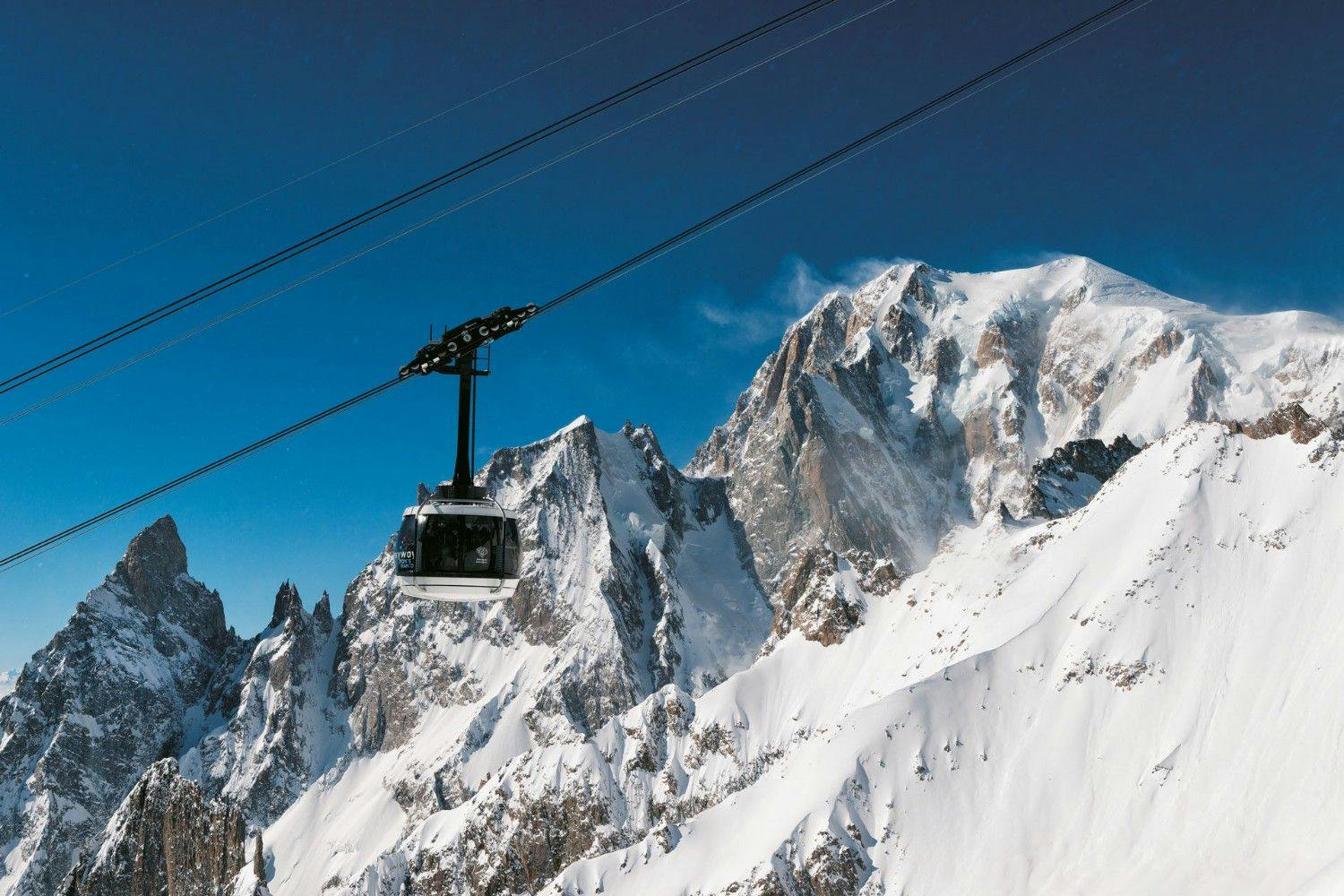 A cablecar on the Skyway Monte Bianco hangs in front of snow-covered Mont Blanc