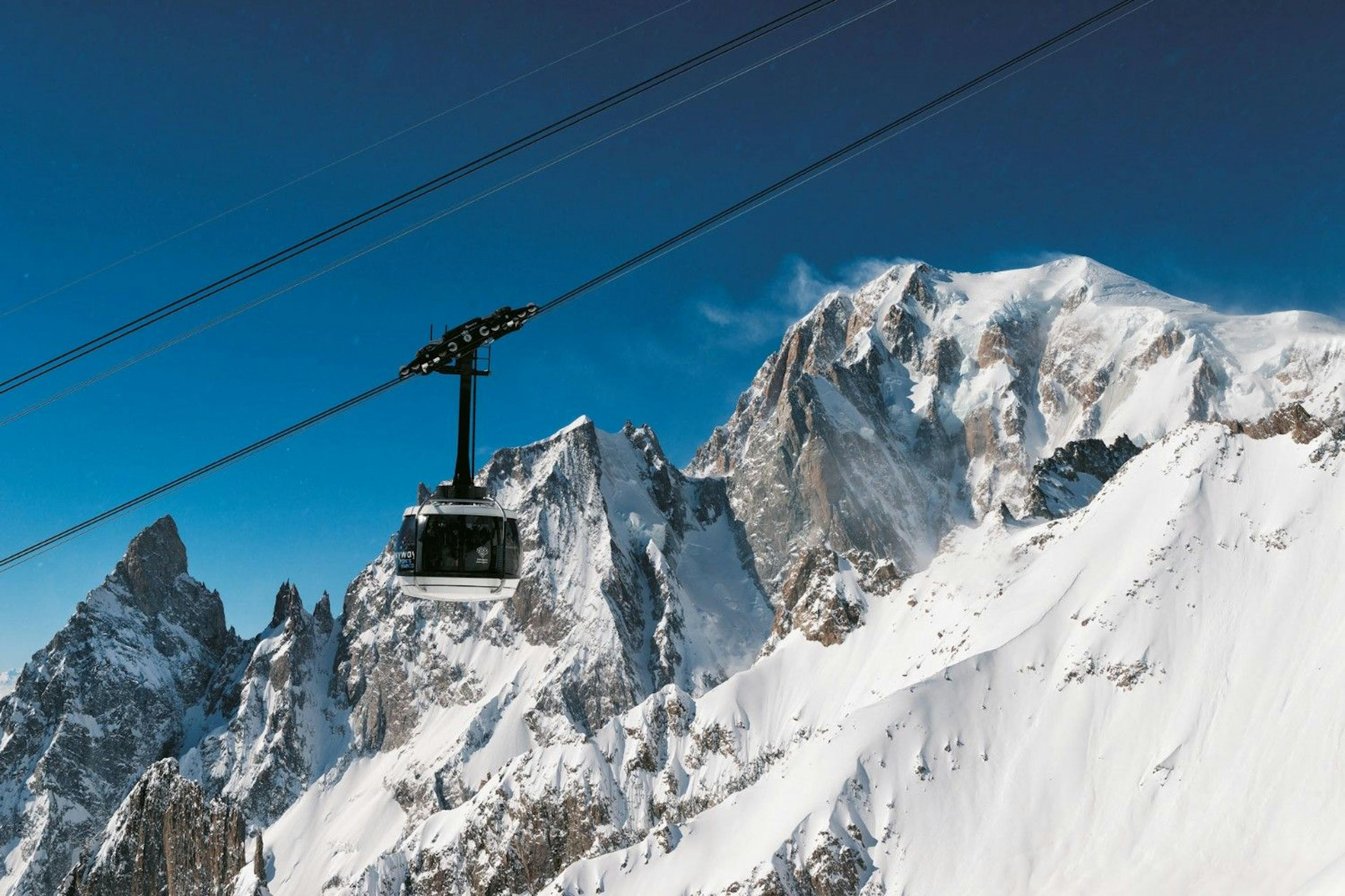 A cablecar on the Skyway Monte Bianco hangs in front of snow-covered Mont Blanc