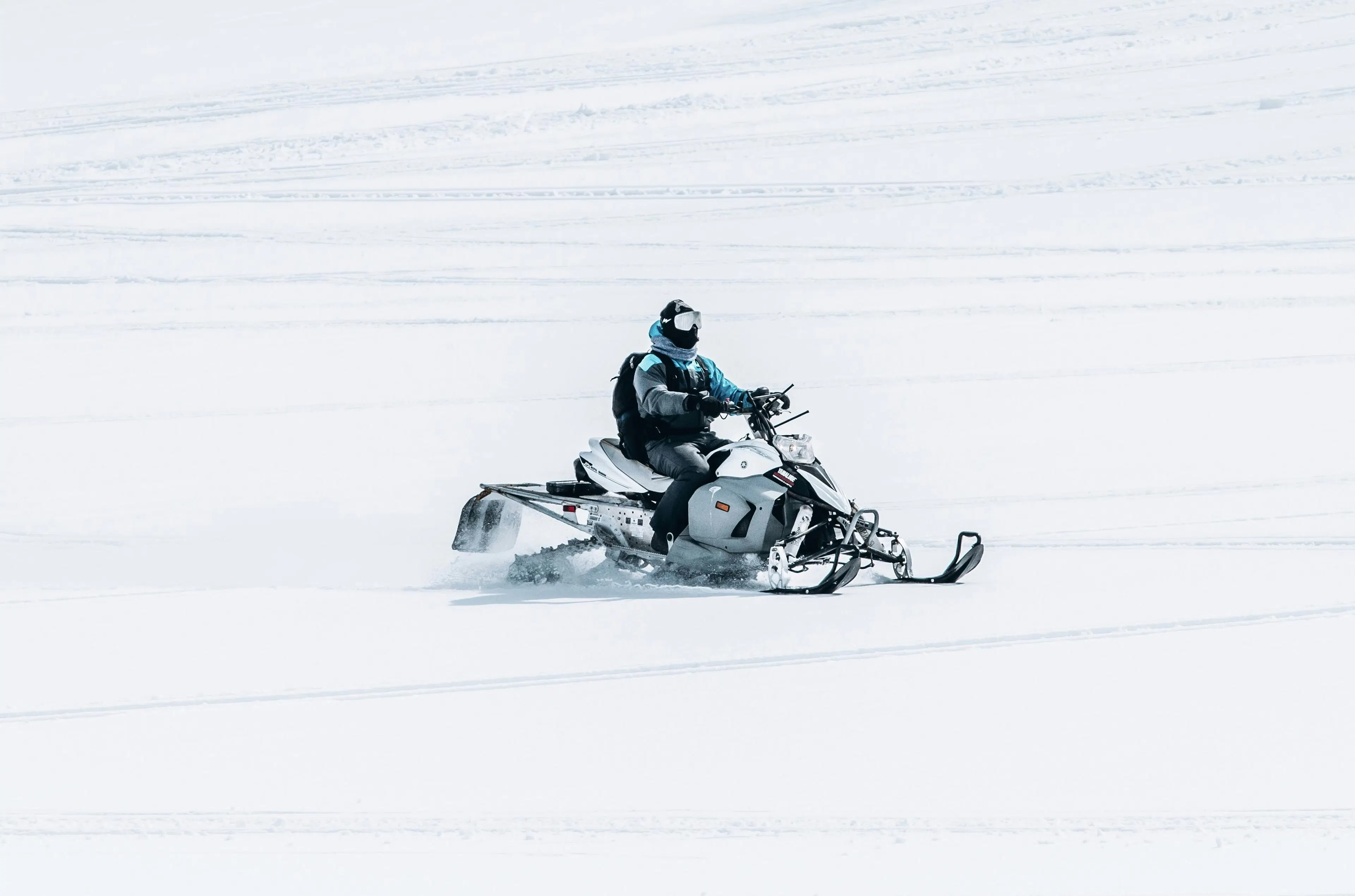 A man riding a snowmobile in a large snowy field