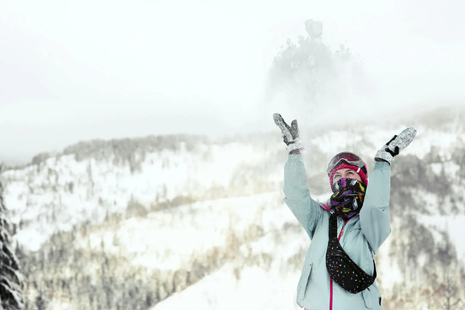 Woman watches how snow falls down on her face while she poses on the winter mountain